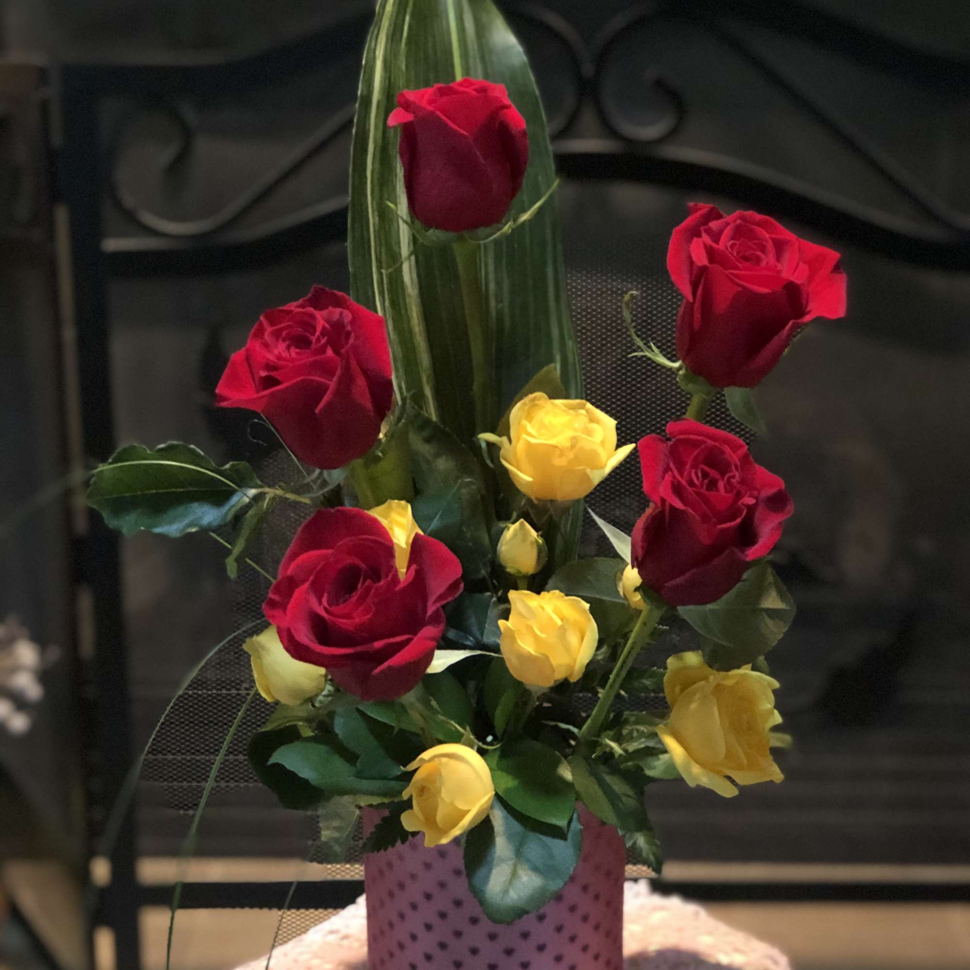 Red and yellow roses arranged in a pink vase
