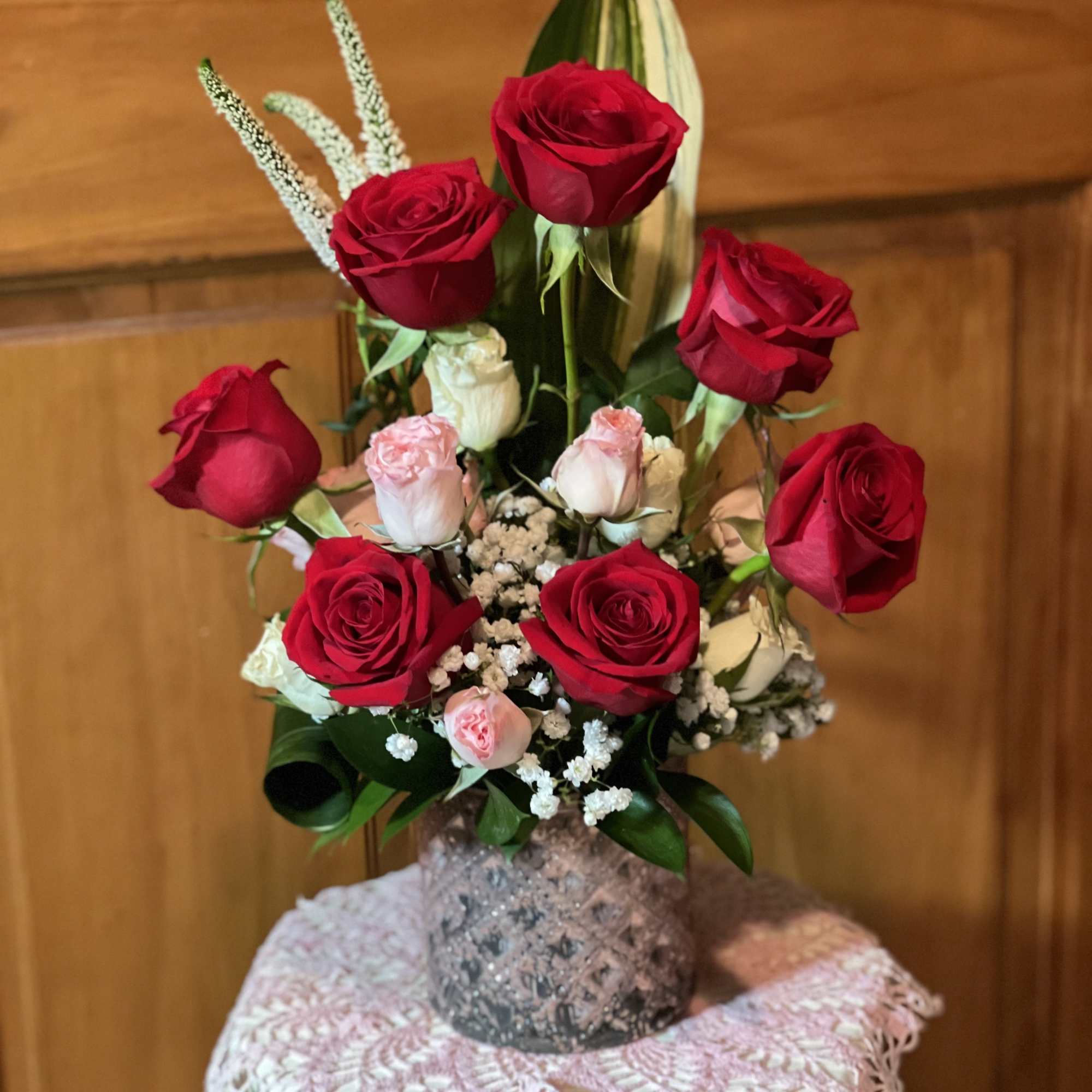 Red and pink roses arranged in a vase with white filler flowers