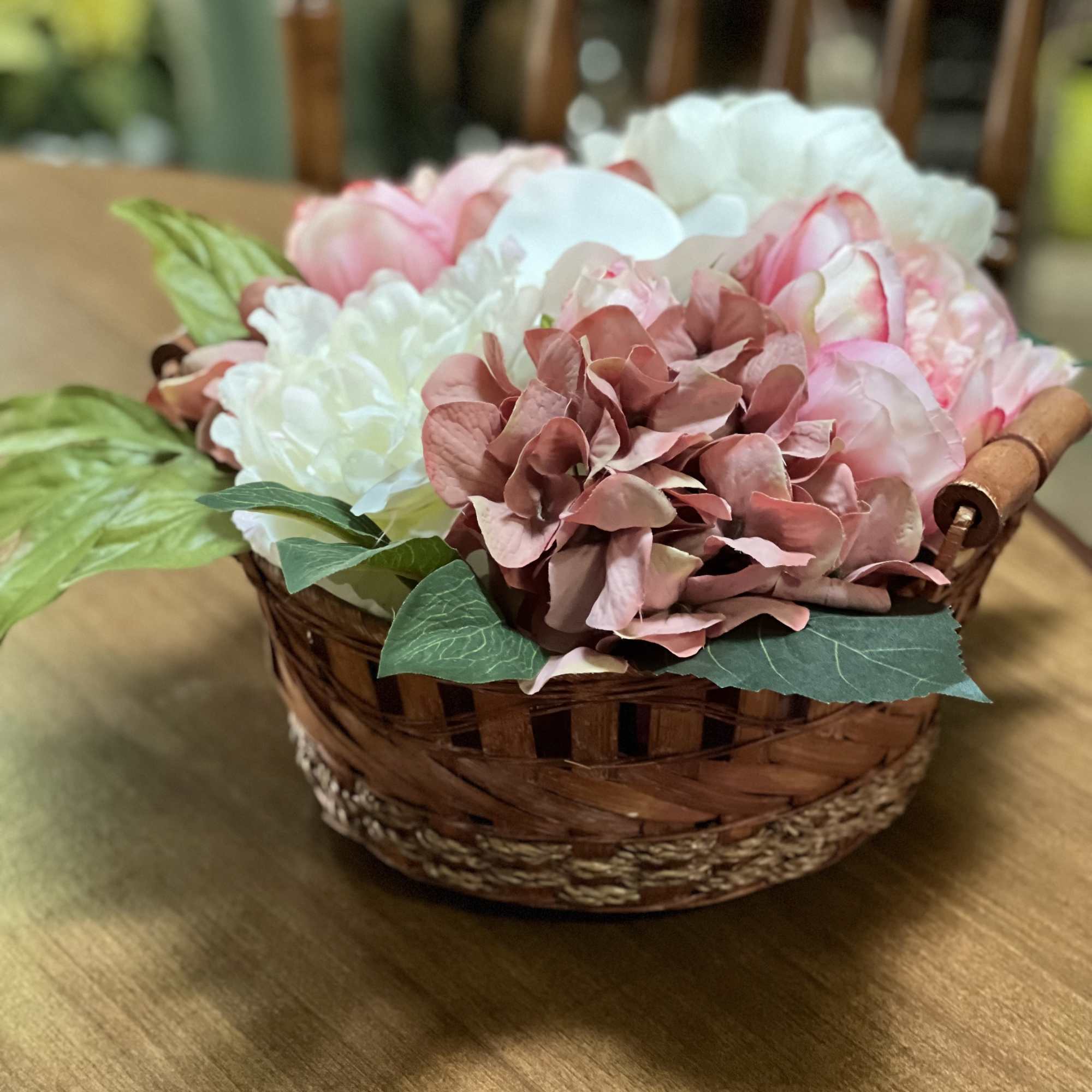 Basket of pink and white flowers on a wooden table