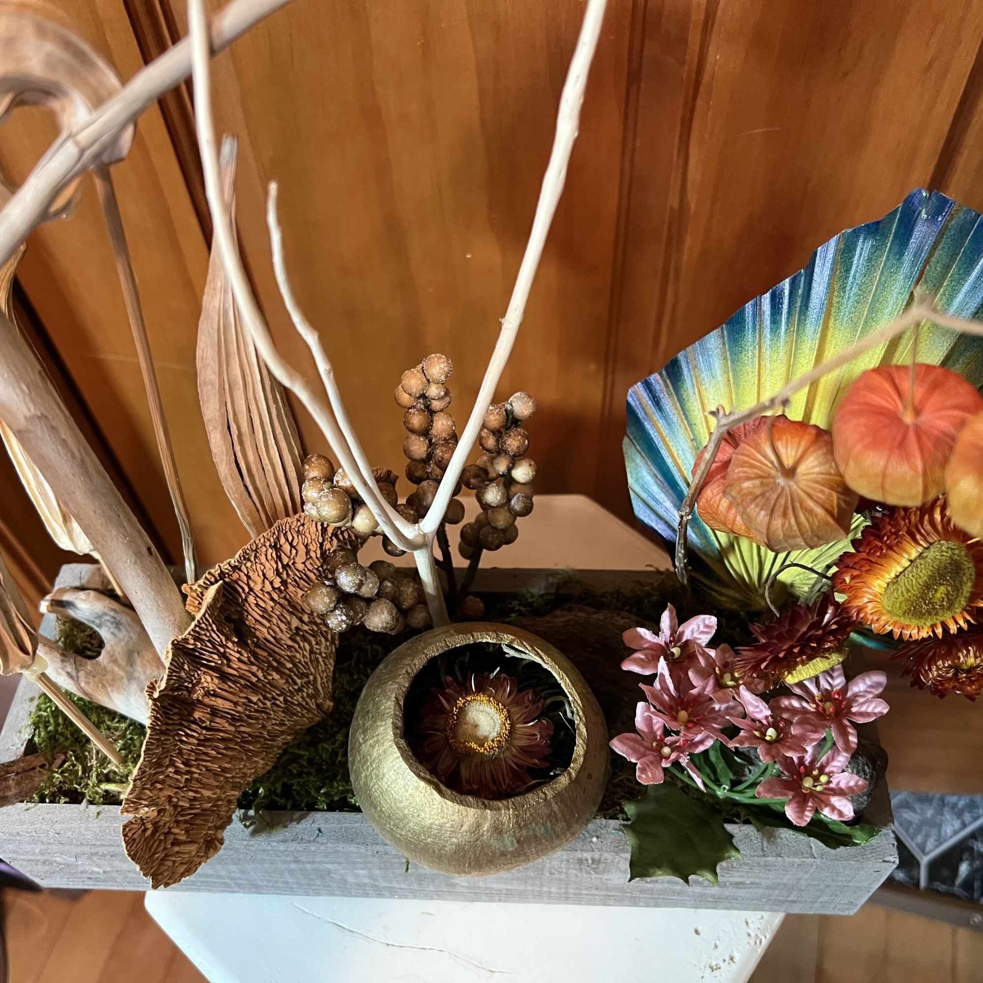 Decorative floral arrangement with dried flowers and seed pods in a rectangular container