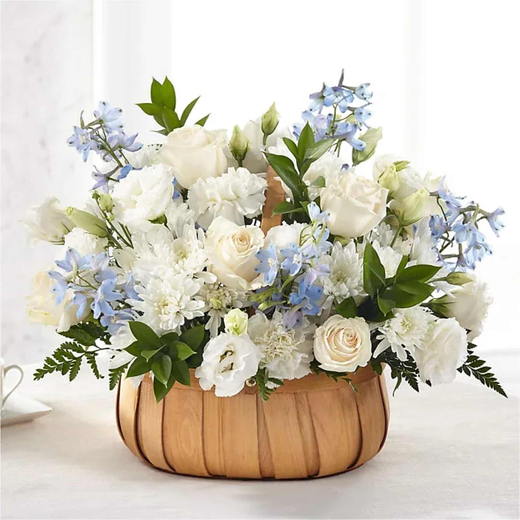 White and pale blue floral arrangement in a woven basket