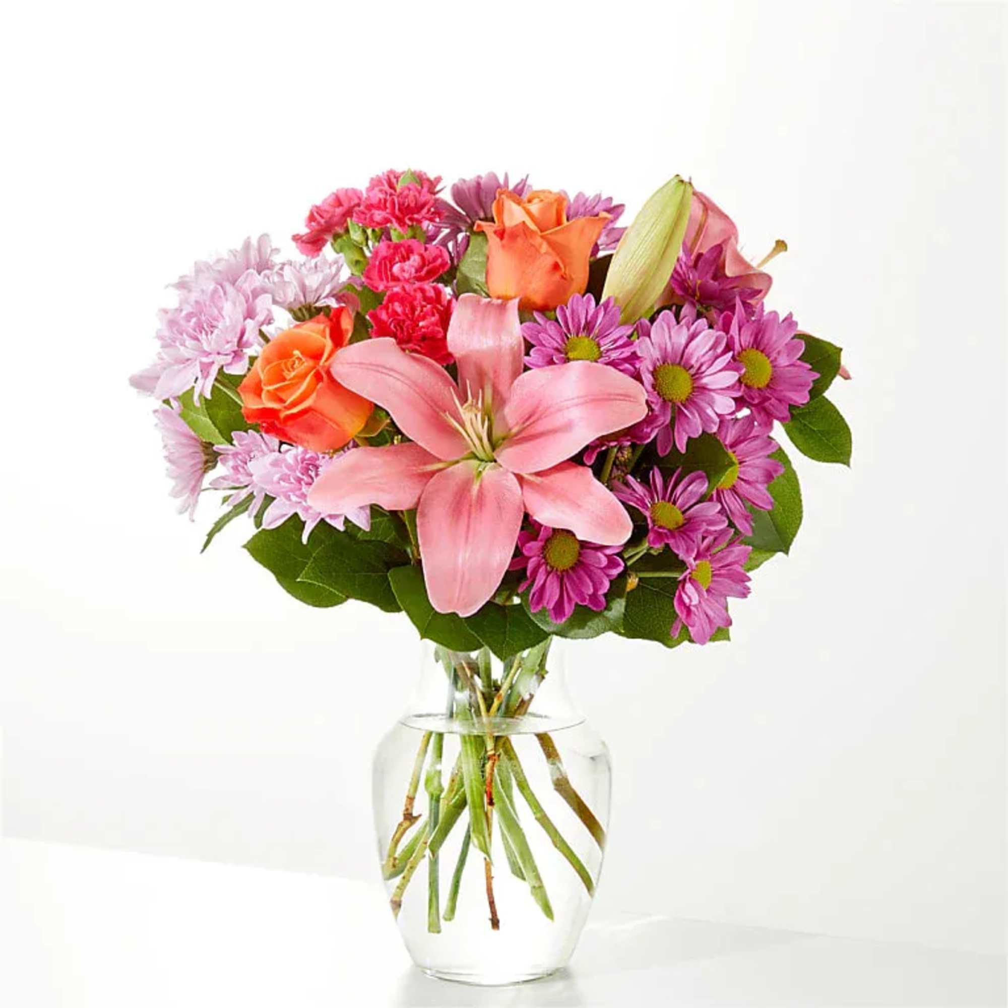 Pink and purple mixed bouquet with orange roses in a clear glass vase