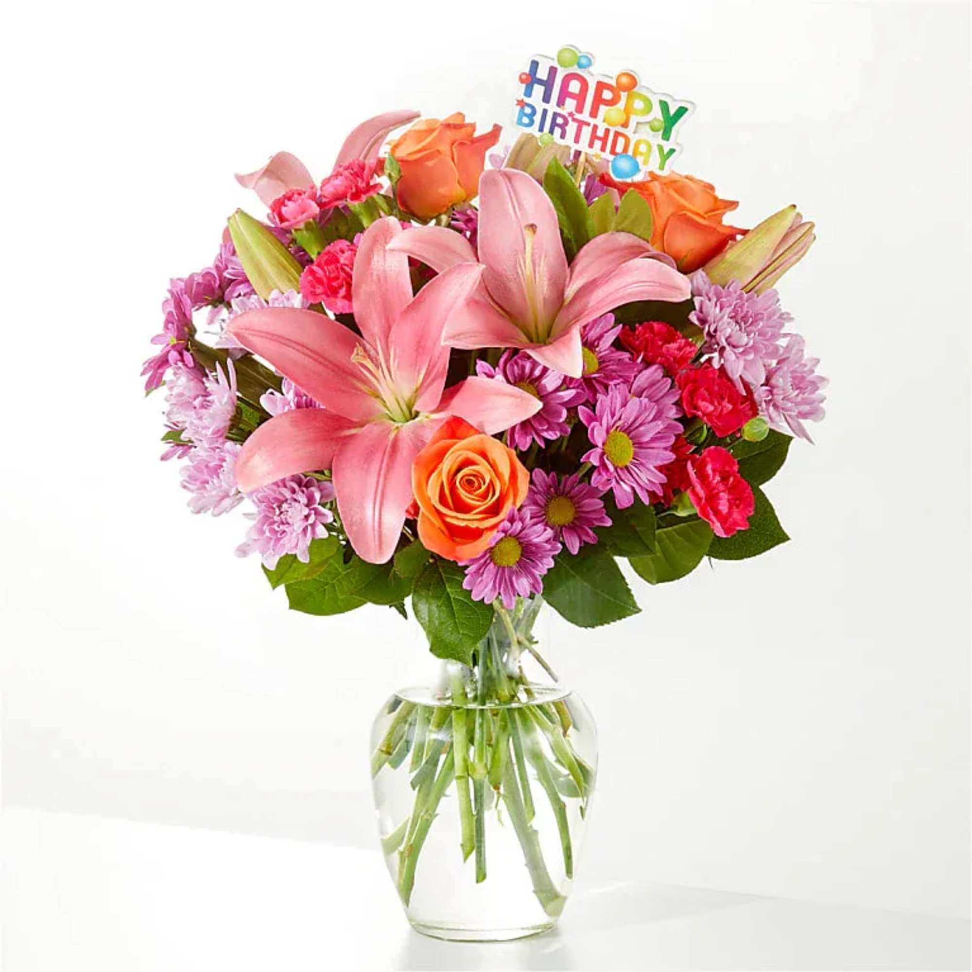 Bouquet of pink lilies, orange roses, and purple daisies in a glass vase