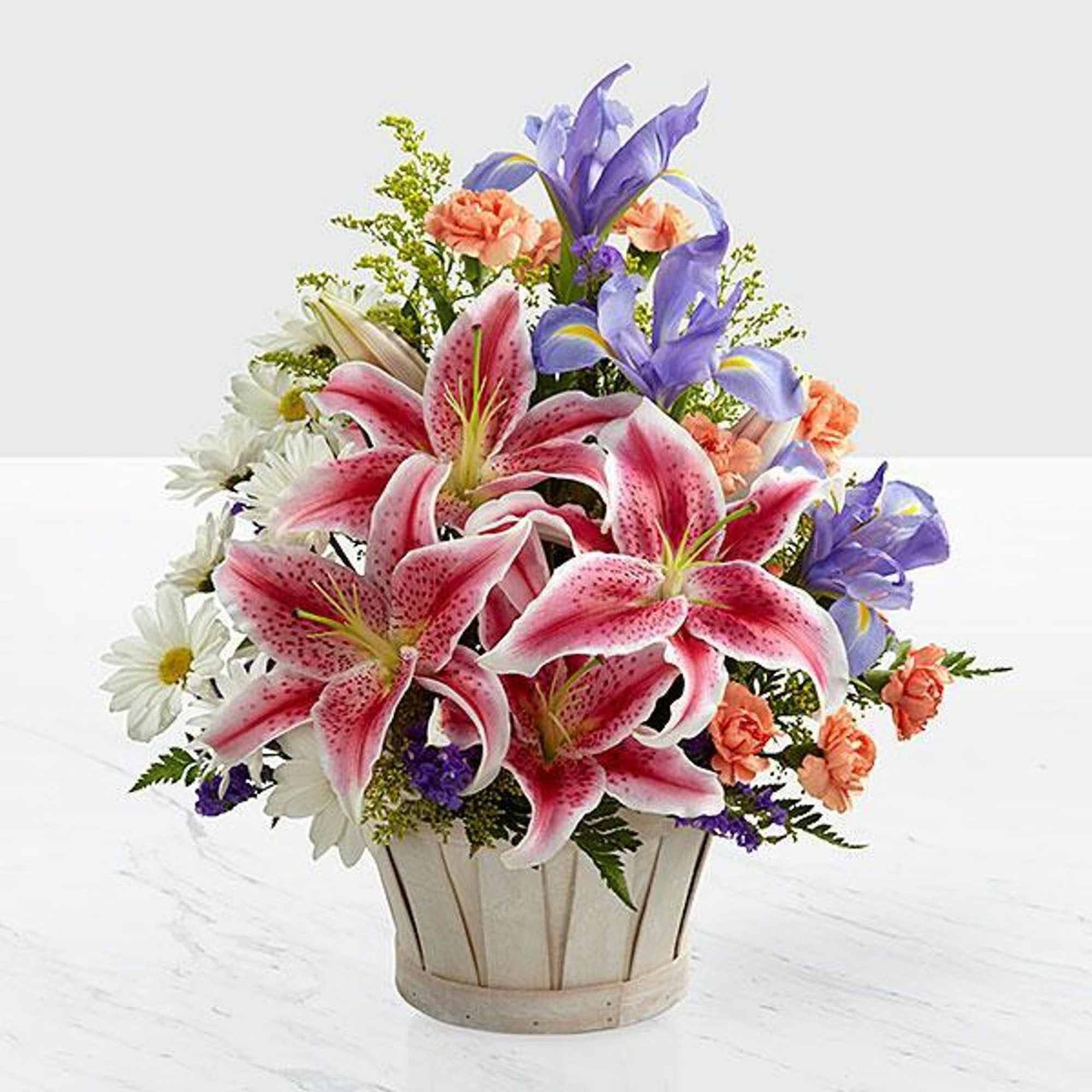 Bouquet of pink lilies, purple irises, and white daisies in a basket