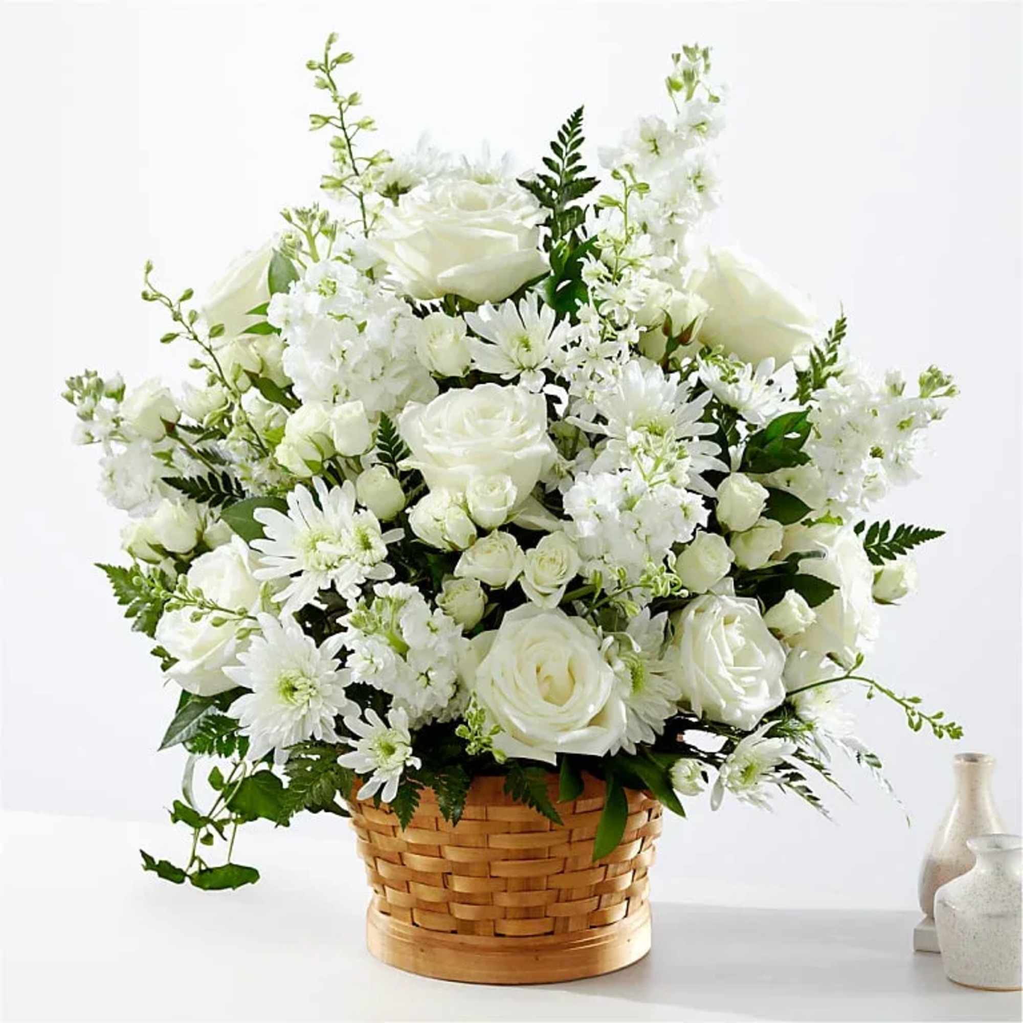 White roses and daisies arranged in a woven basket