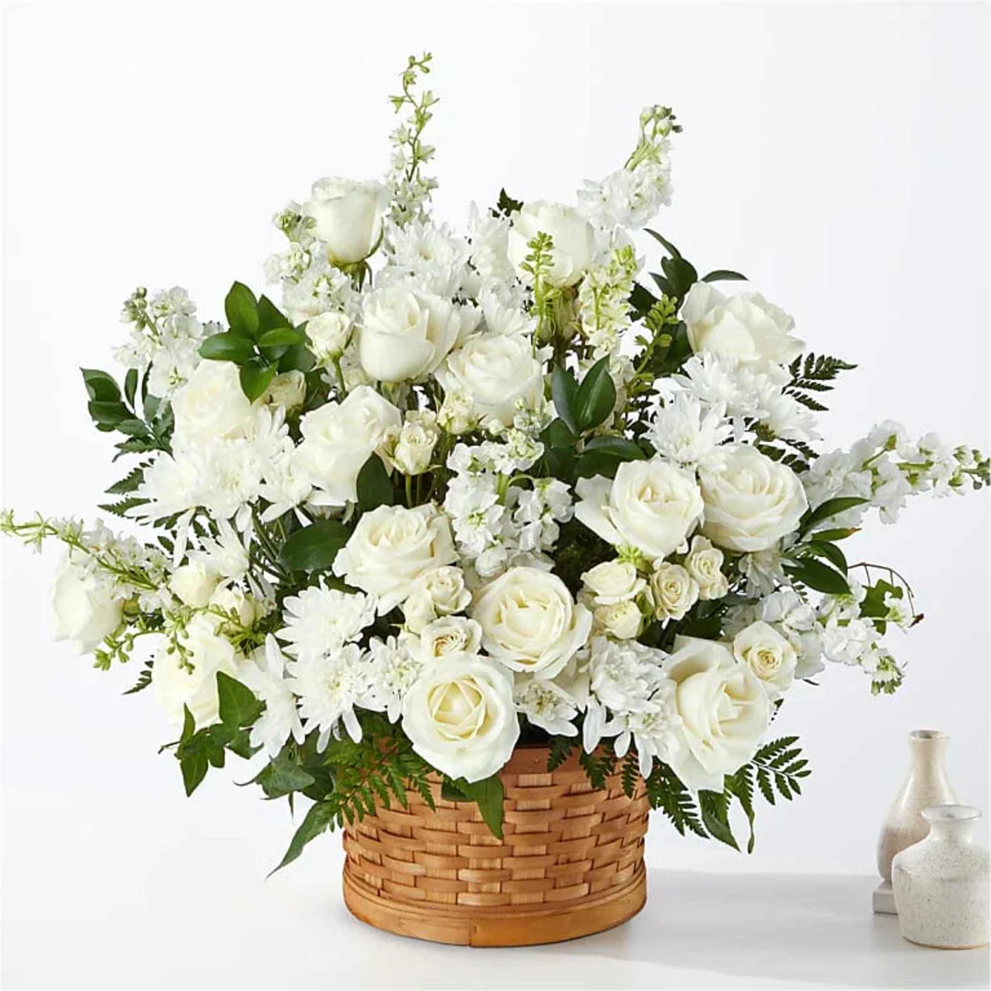 White roses and daisies arranged in a woven basket