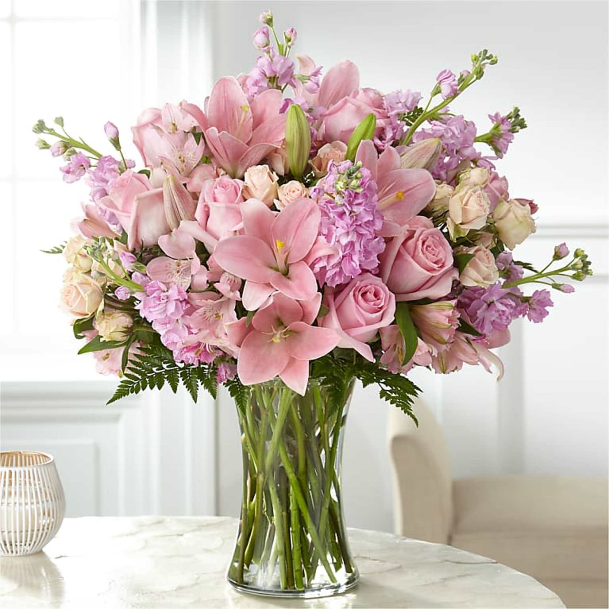 Pink lilies and roses arranged in a clear glass vase