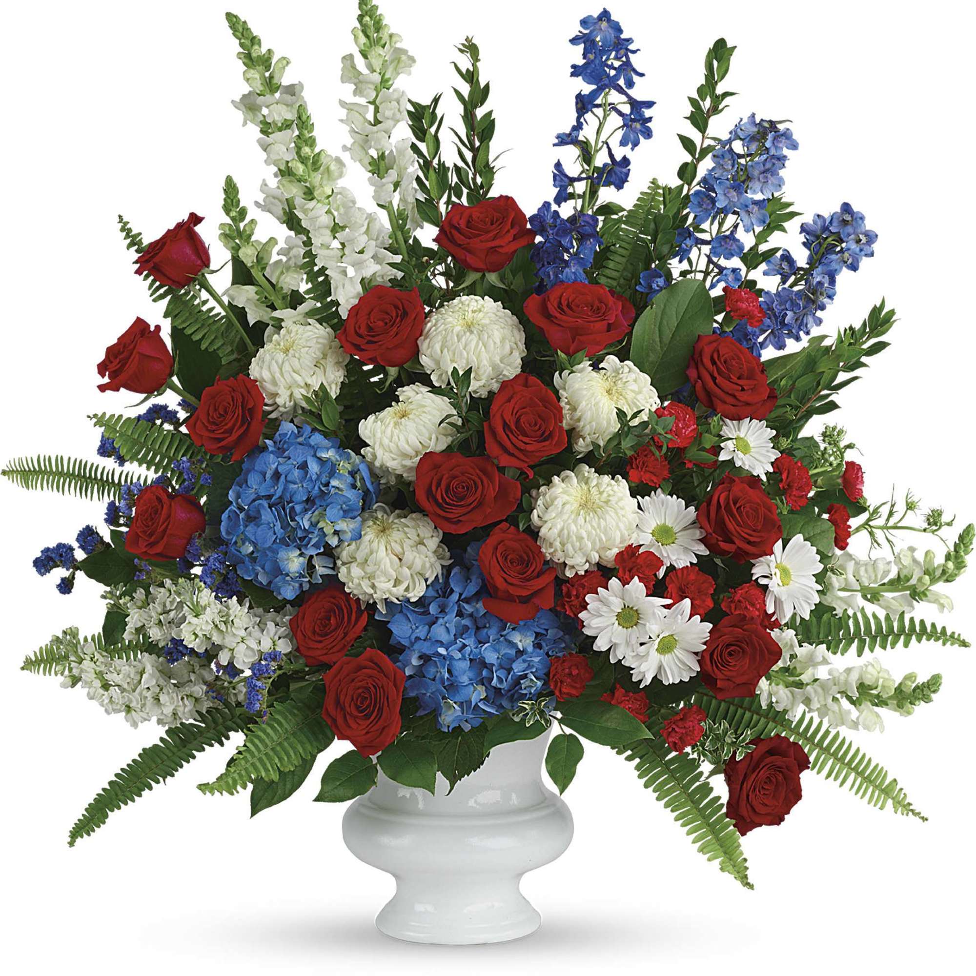 Red roses, blue flowers, and white blooms in a white urn vase