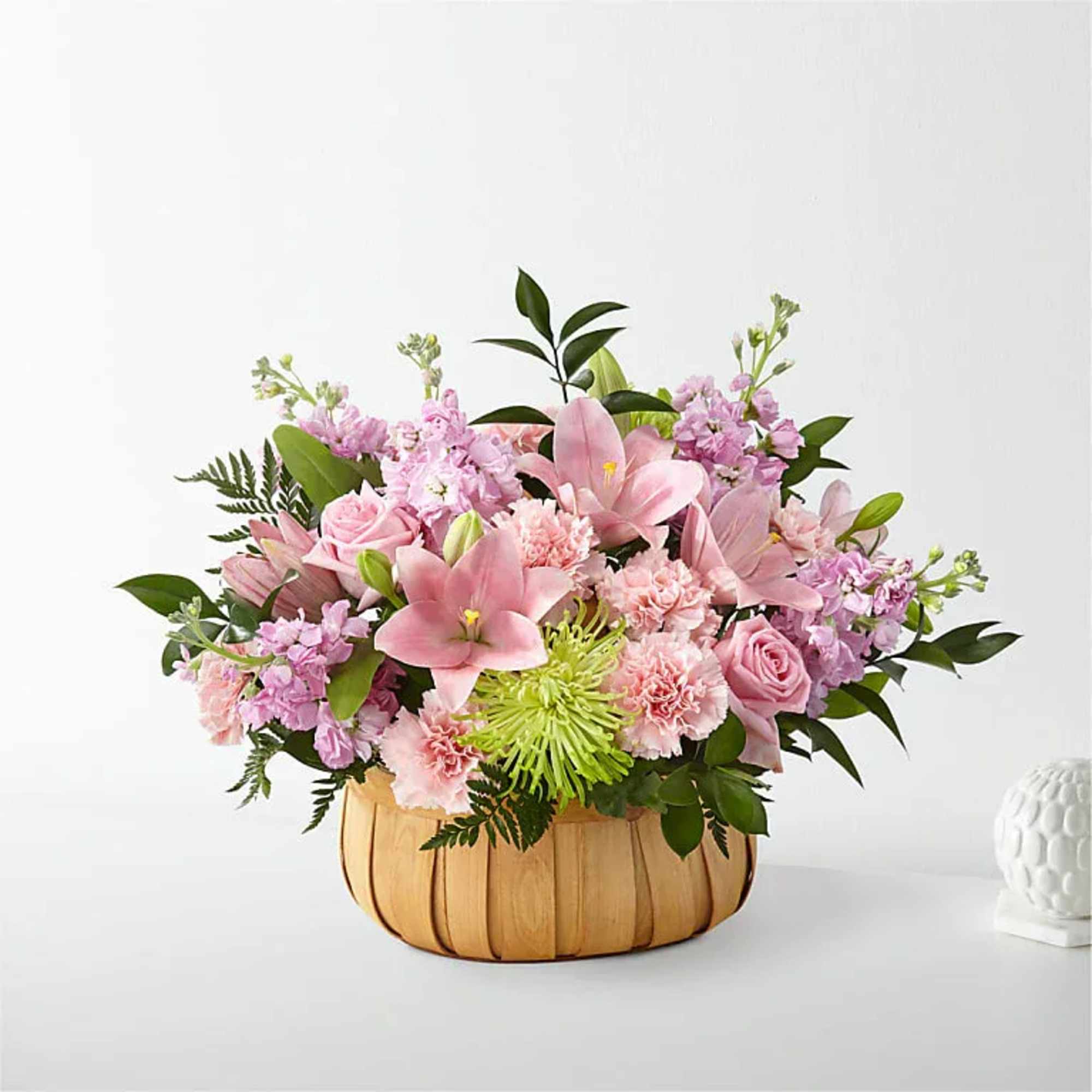 Pink floral arrangement in a woven basket container