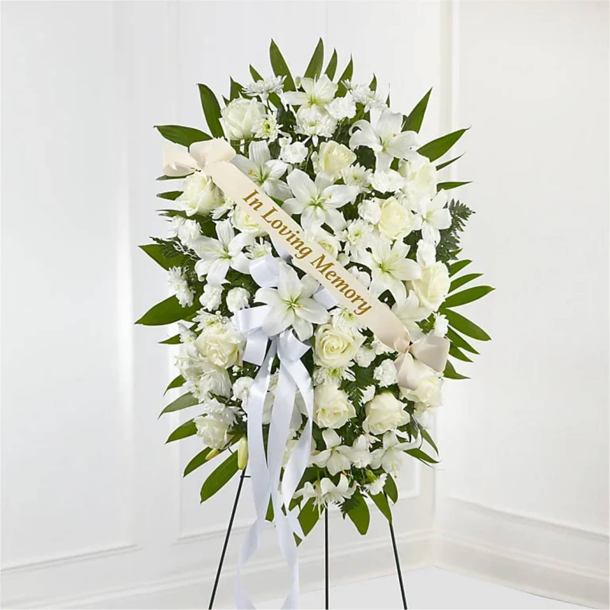 White funeral wreath on an easel with a memorial ribbon
