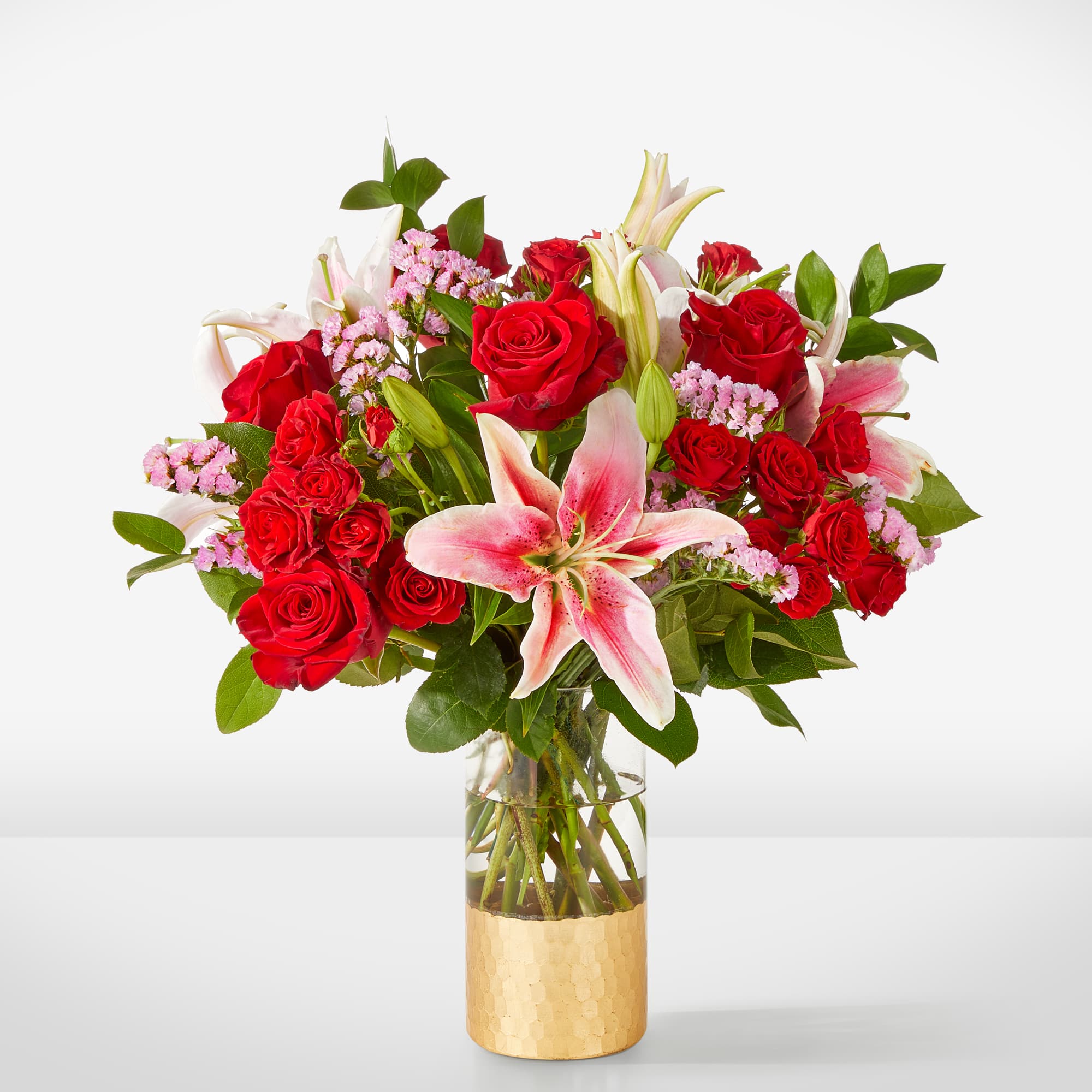 Red roses and pink lilies in a clear glass vase
