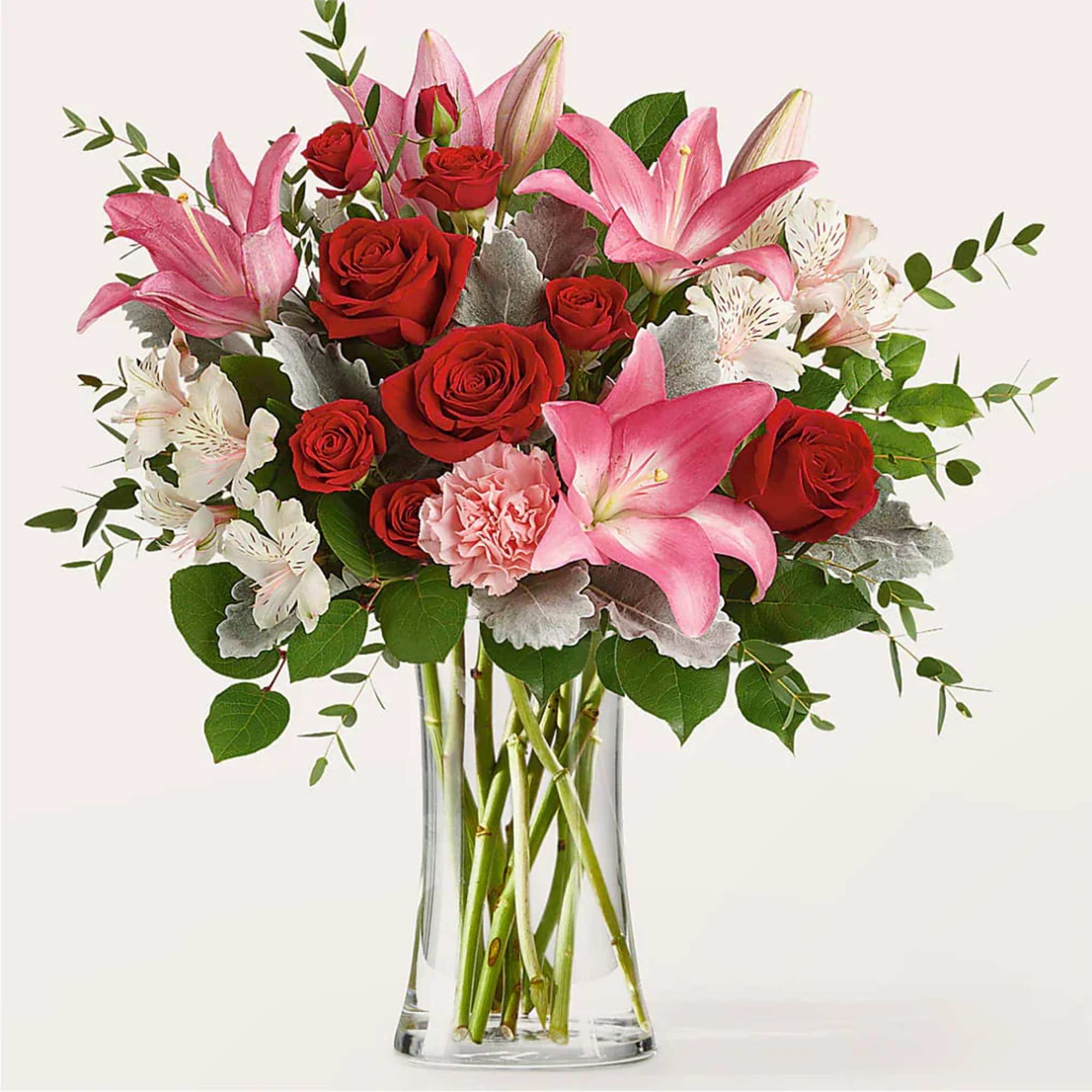 Bouquet of red roses and pink lilies in a clear glass vase
