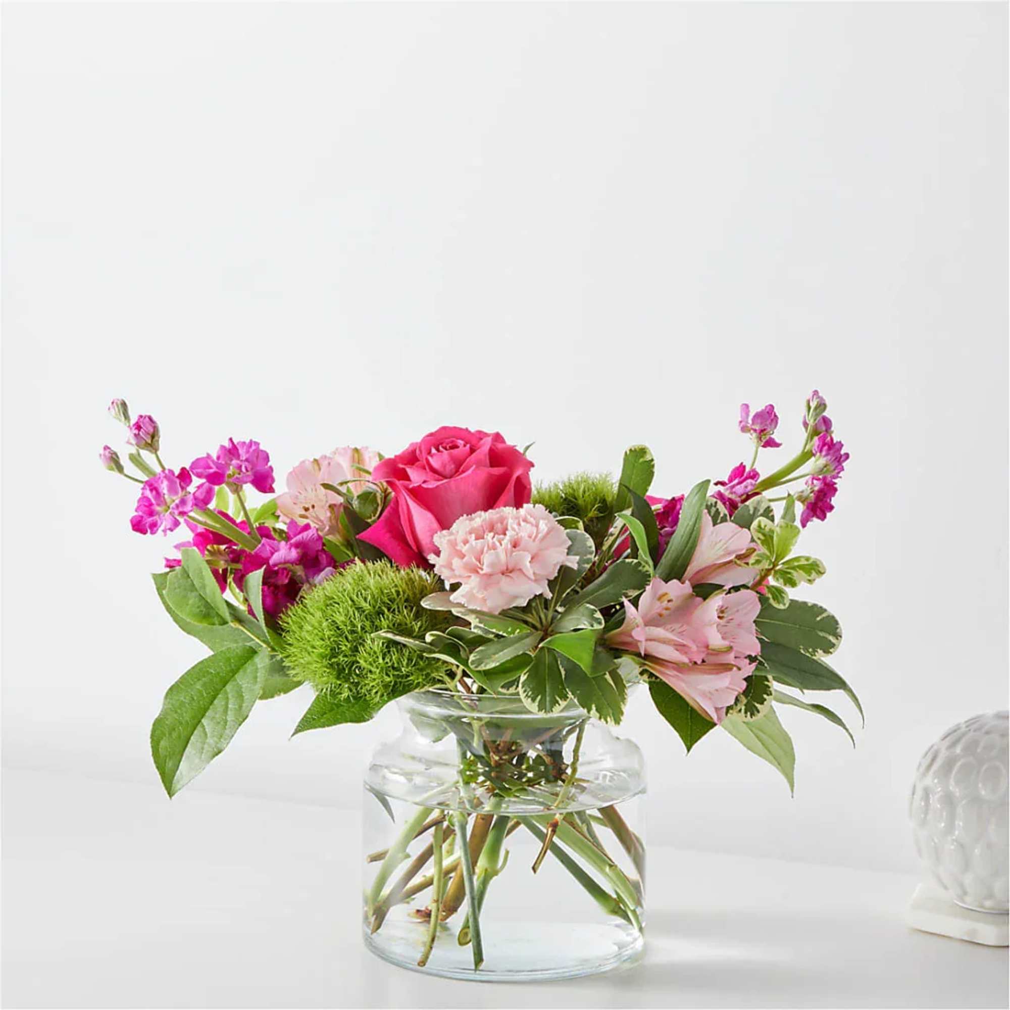 Pink rose and carnations in a clear glass vase