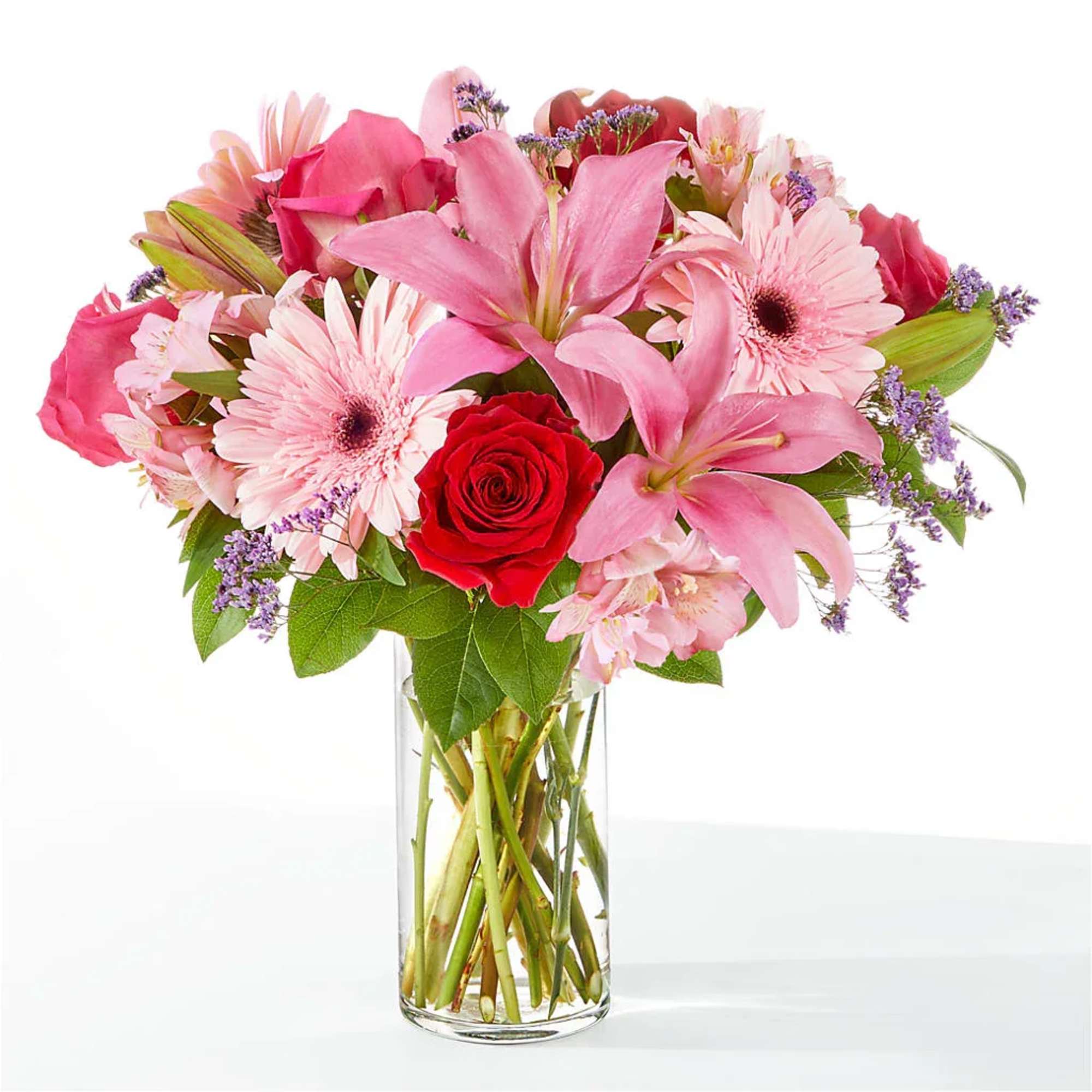 Pink bouquet with lilies, roses, and daisies in a clear glass vase