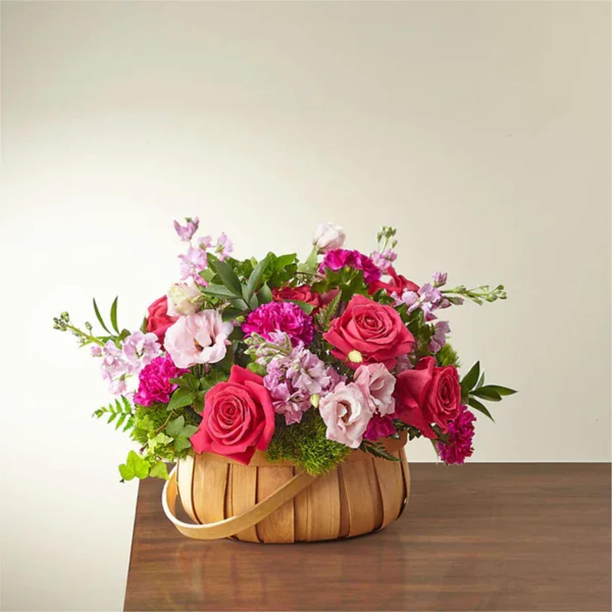 Basket arrangement of pink roses and lilac flowers