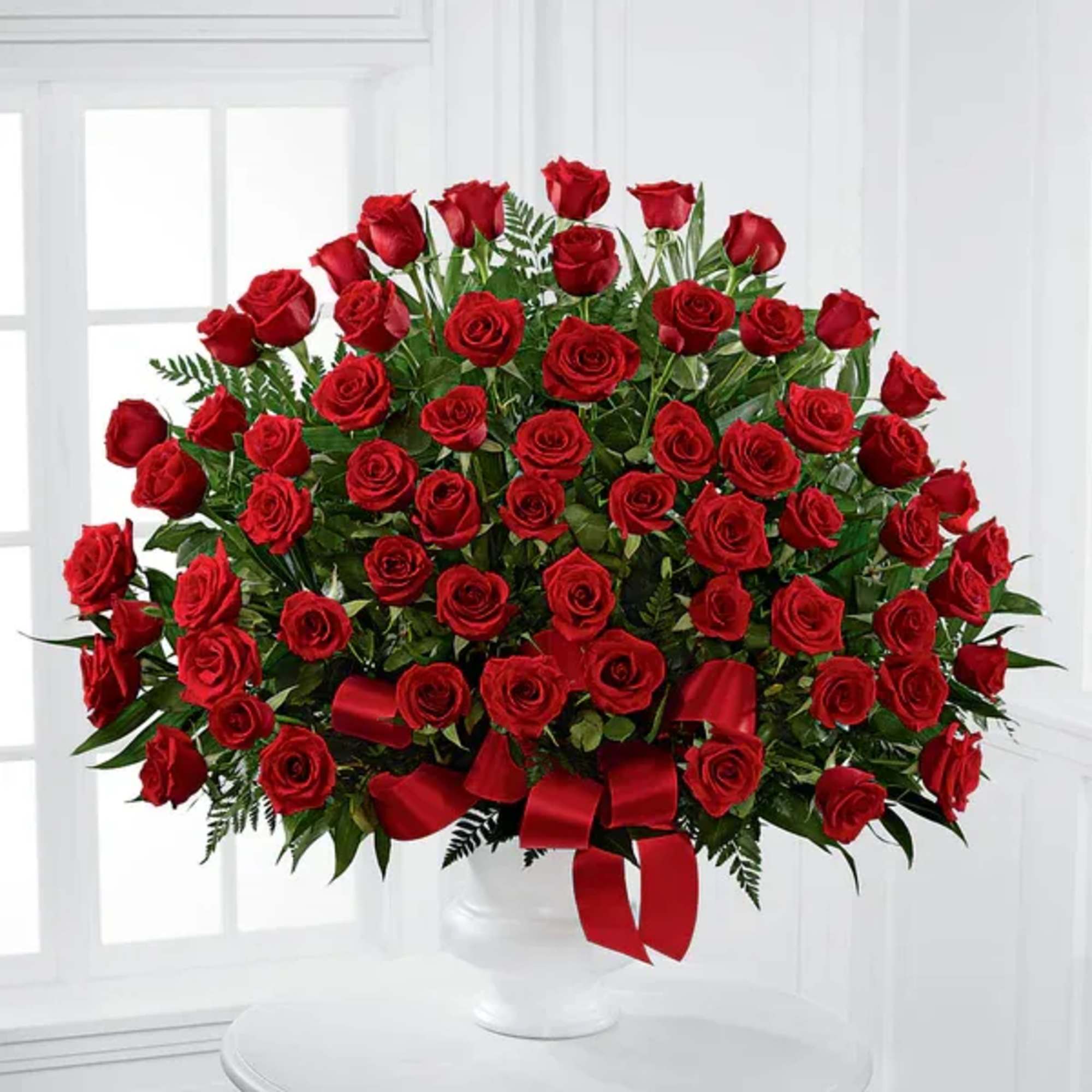 Large bouquet of red roses in a white vase with a red ribbon
