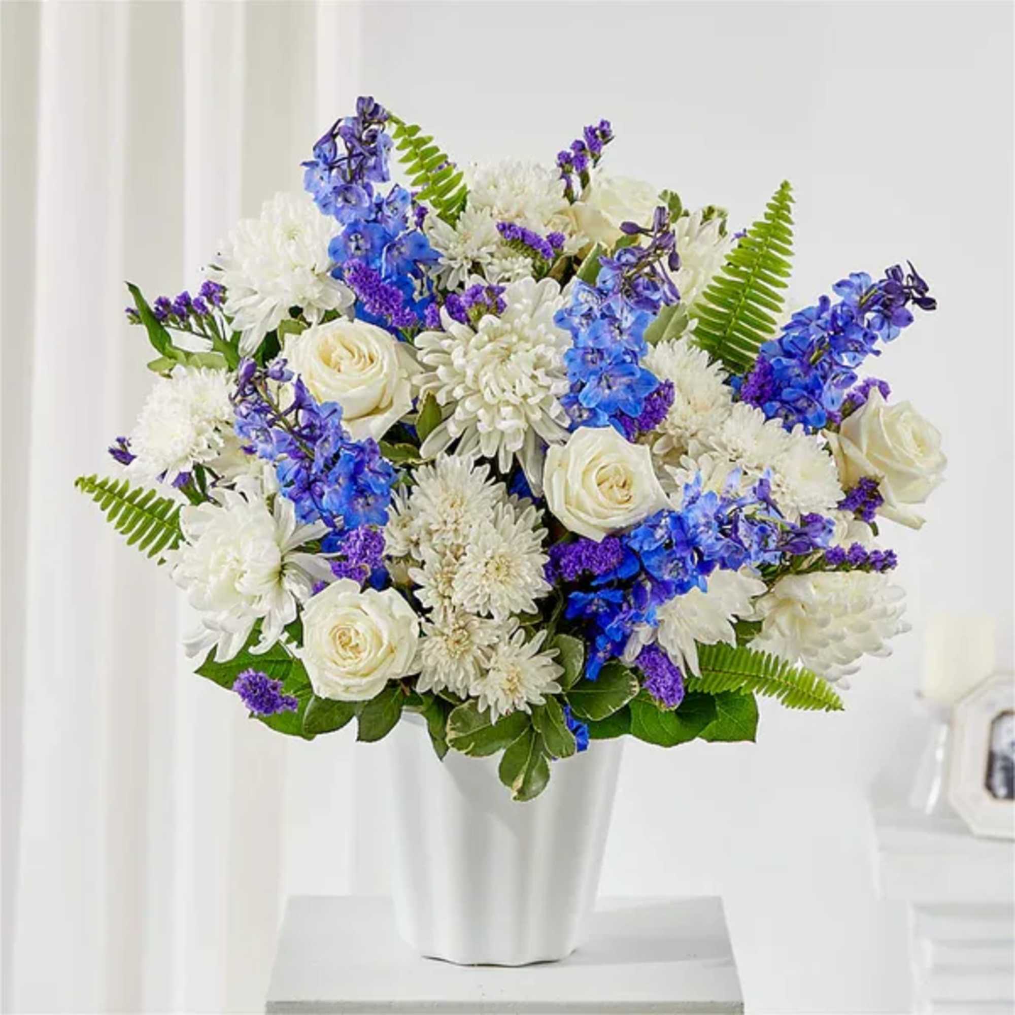 White and blue floral arrangement in a white vase