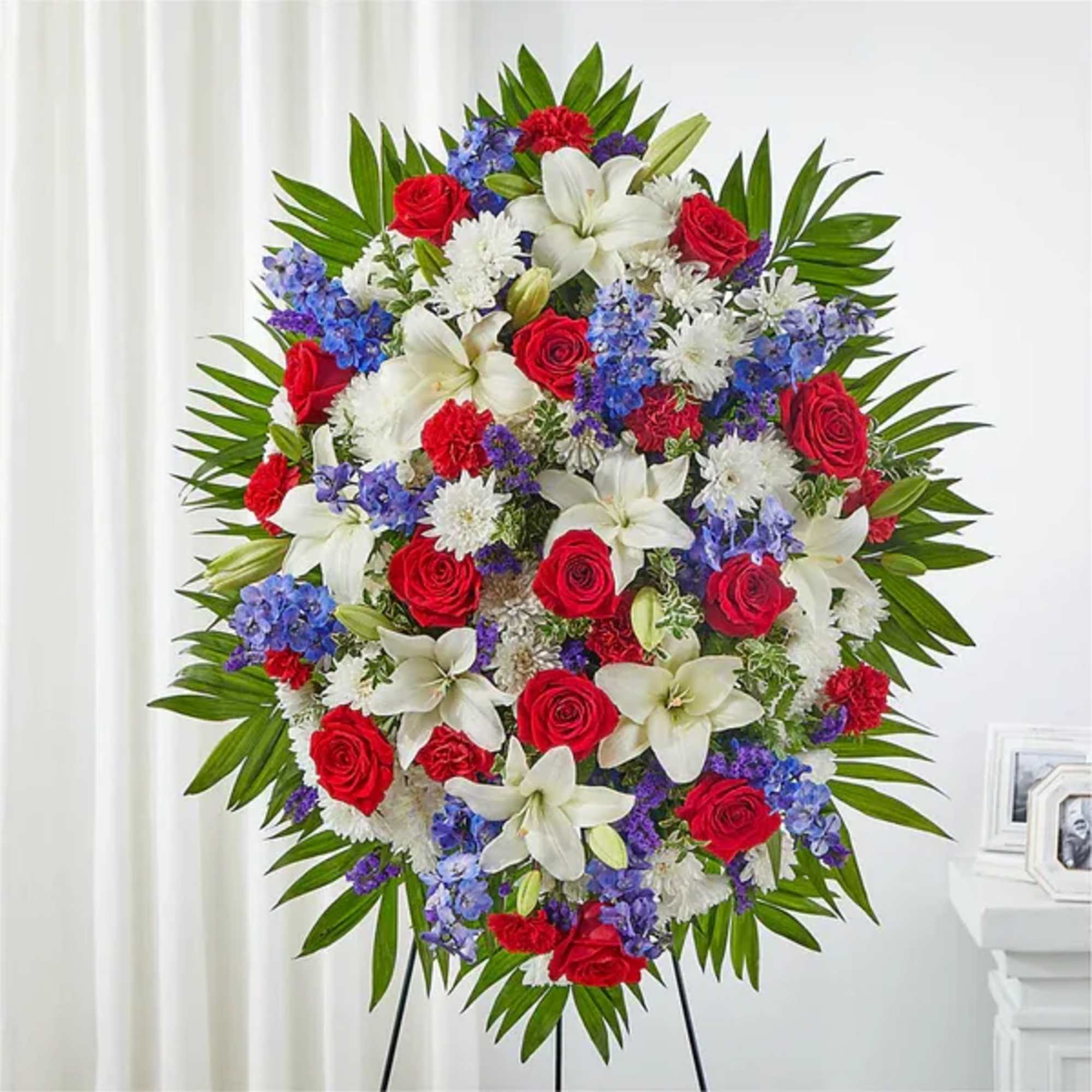 Standing floral spray with red roses, white lilies, and blue flowers