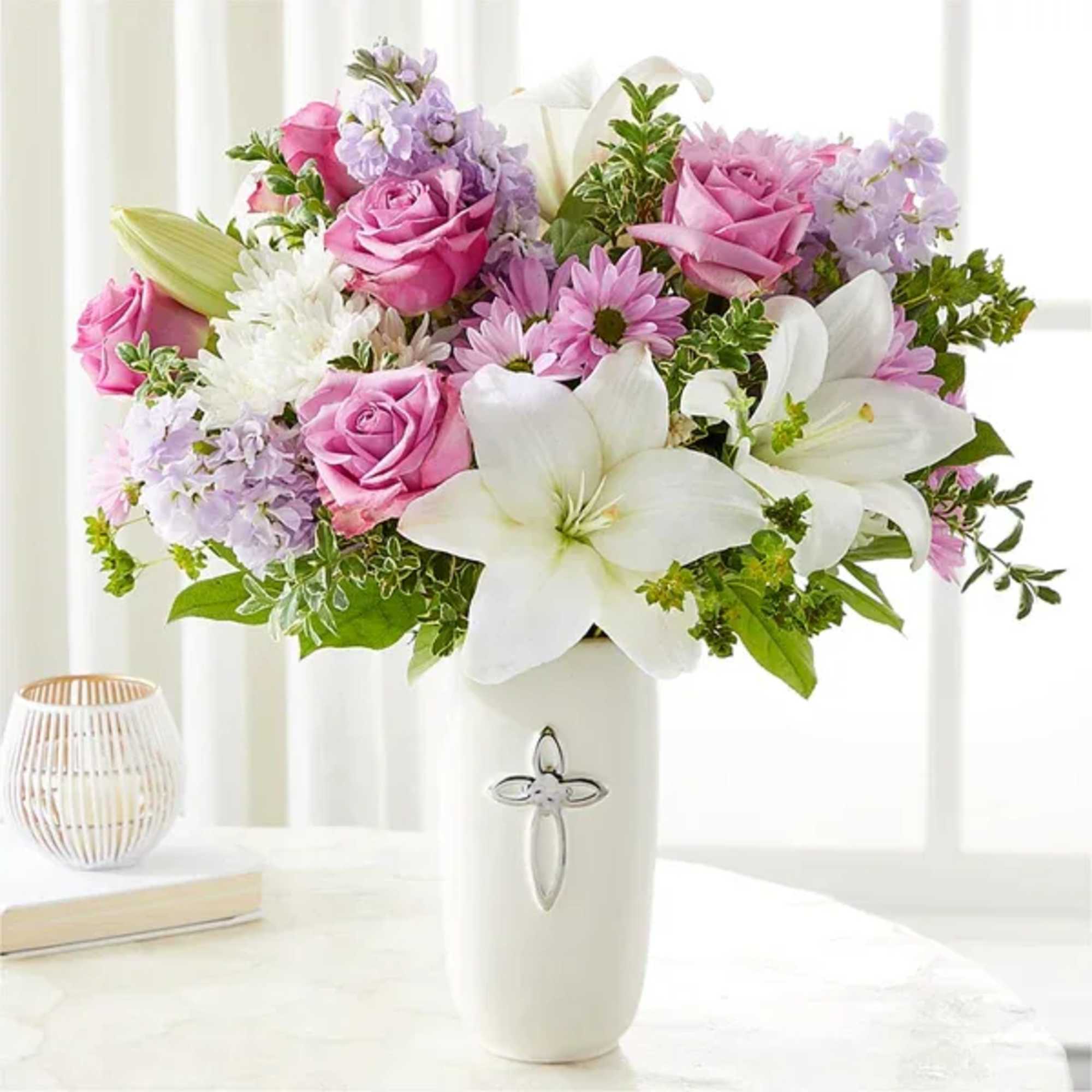 Pink roses and white lilies in a white vase with a cross emblem