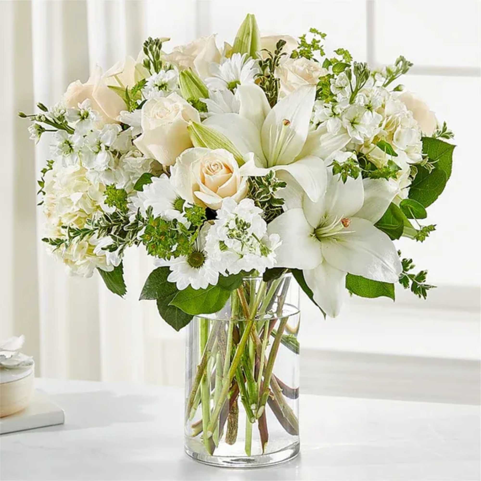 White lilies and roses arranged in a clear glass vase