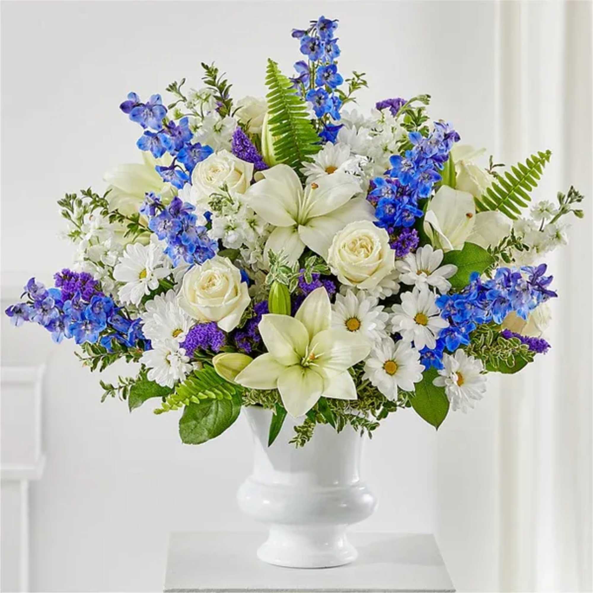 Blue and white floral arrangement in a white pedestal vase