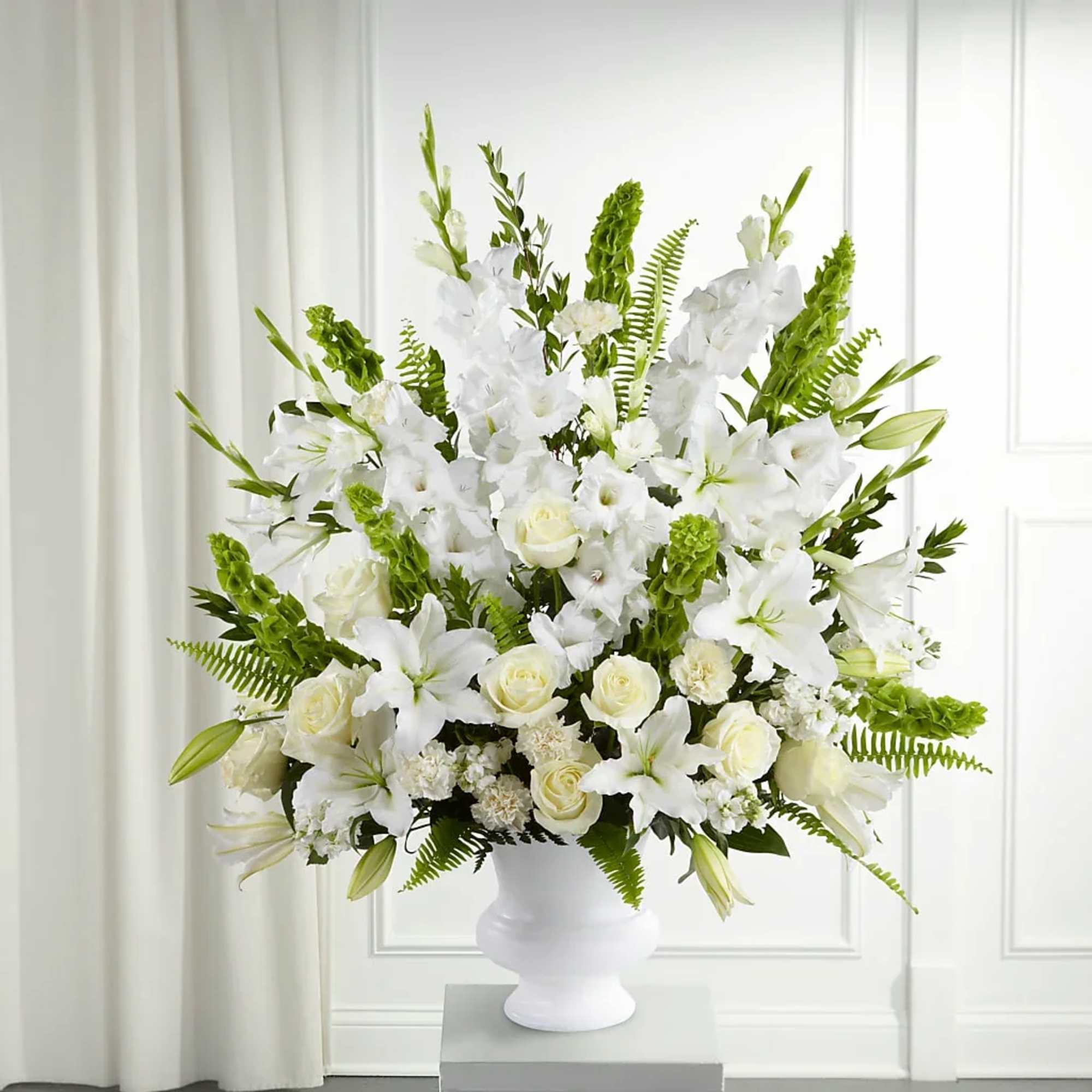 White floral arrangement in a white vase with green accents