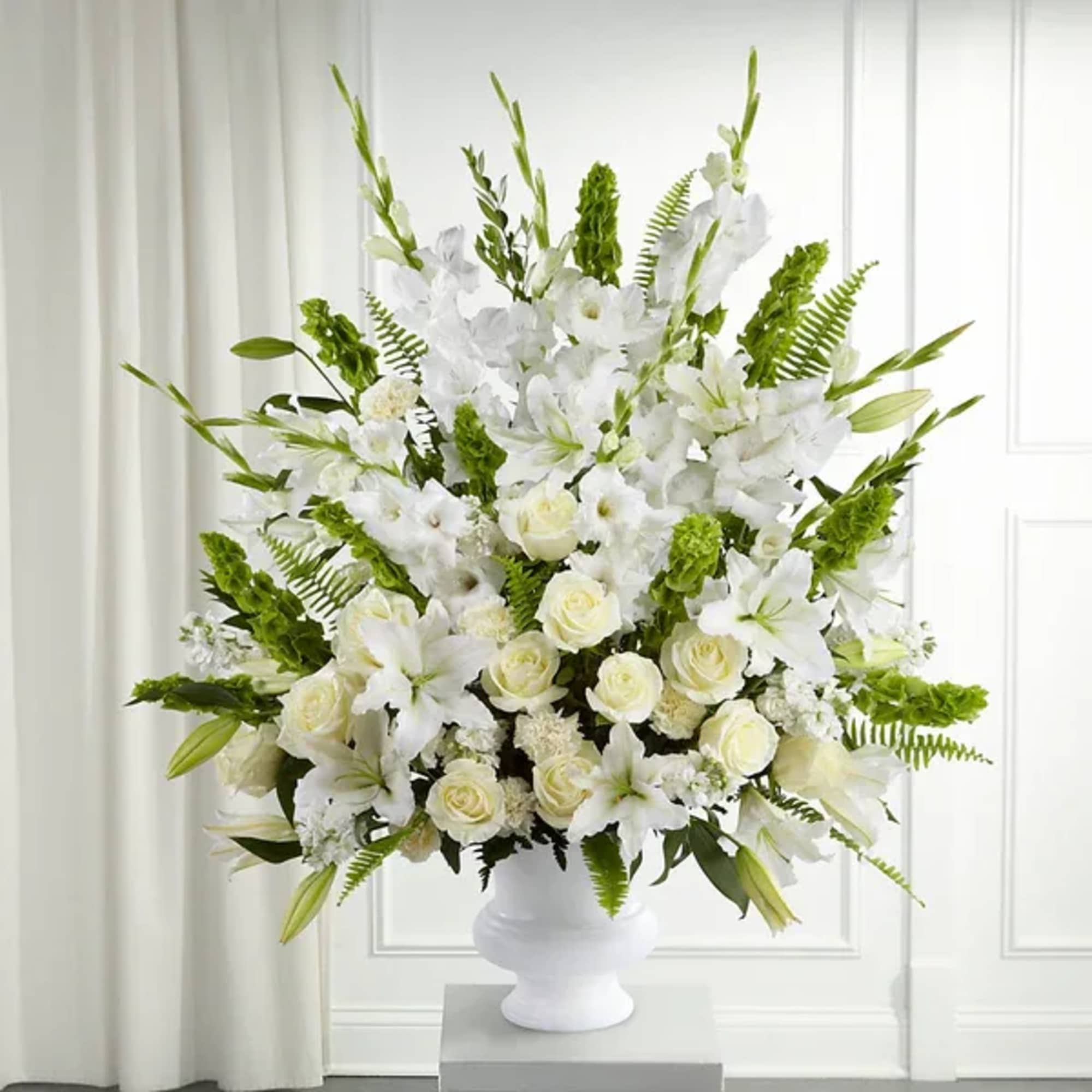 White floral arrangement in a white urn vase
