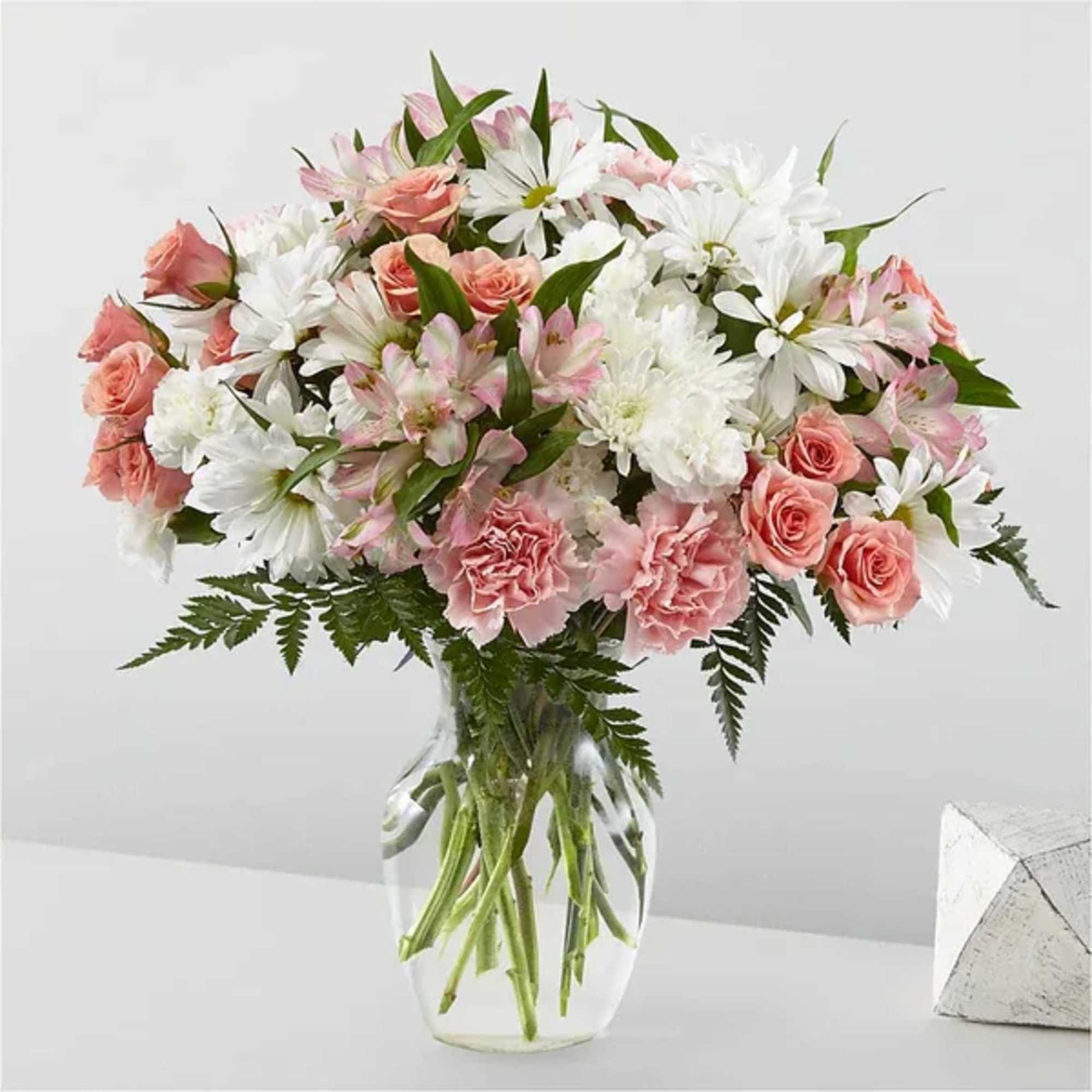 Pink roses and white daisies in a clear glass vase