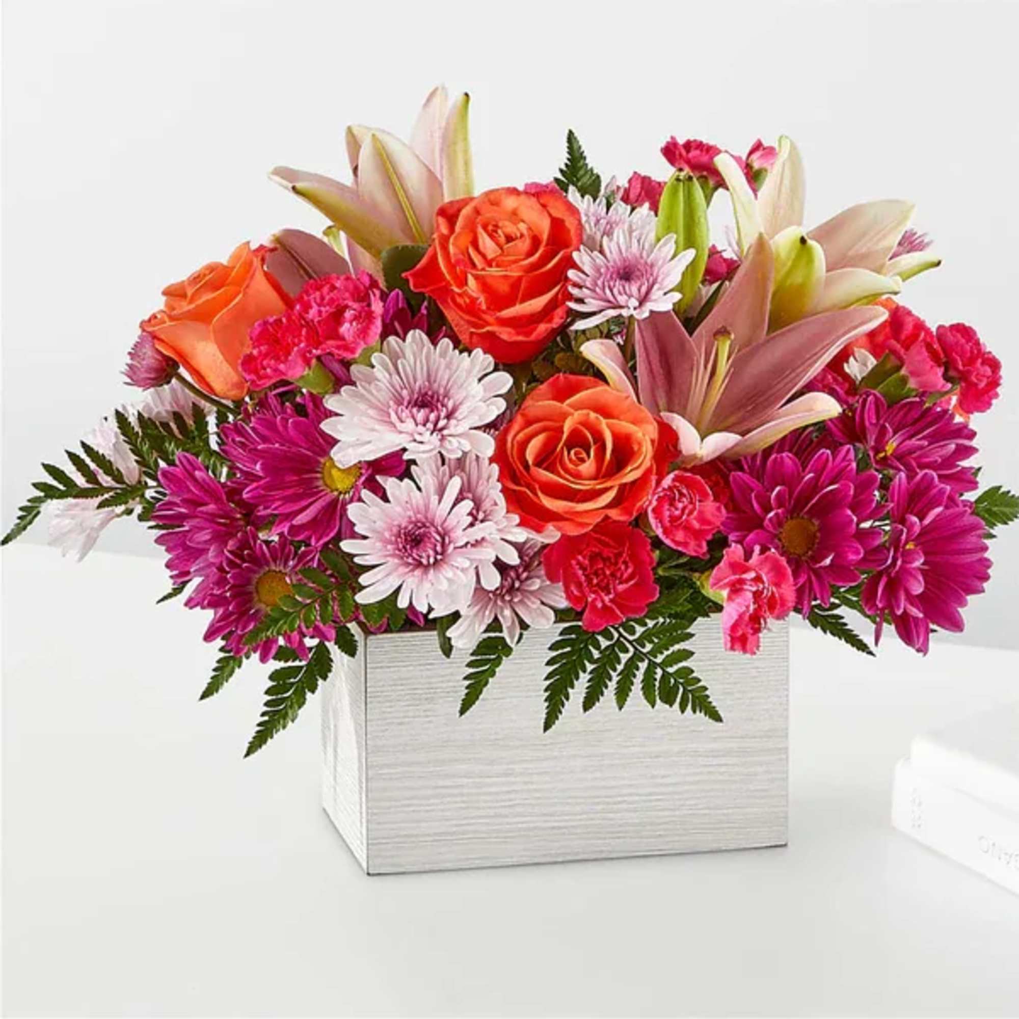 Bright mixed bouquet in a white square box with orange roses and pink daisies