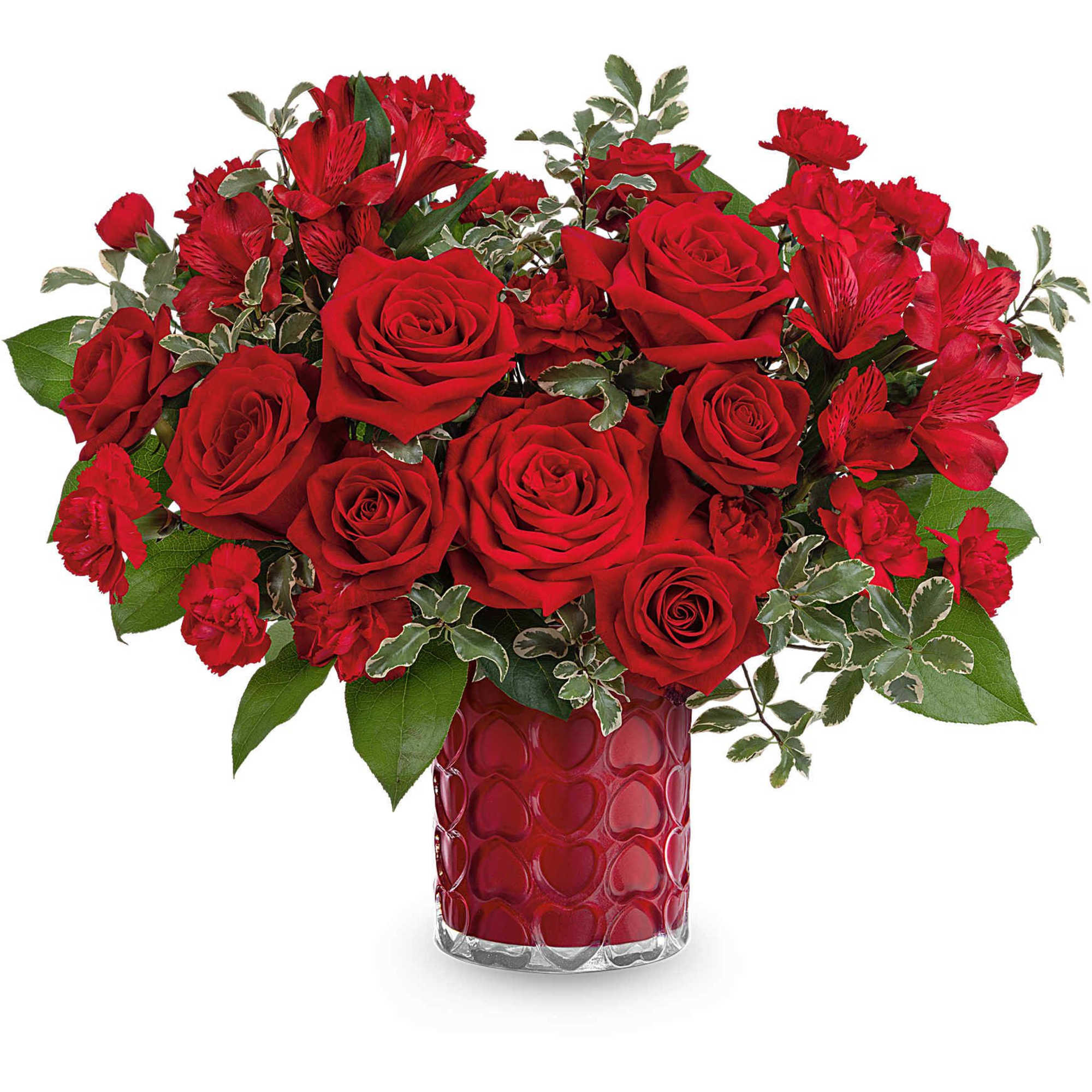 Red roses and carnations in a heart-patterned glass vase