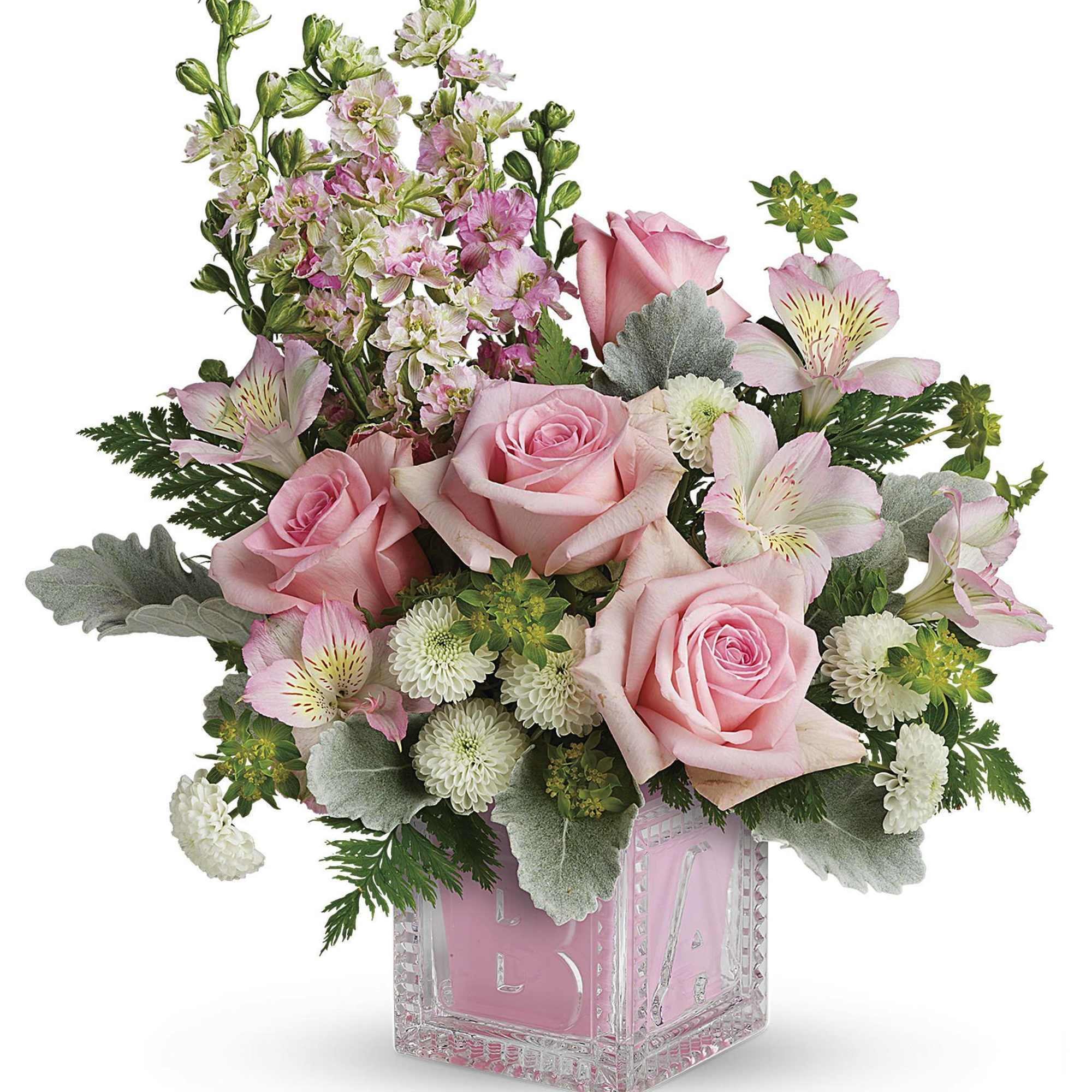 Pink roses and mixed flowers arranged in a clear glass cube vase