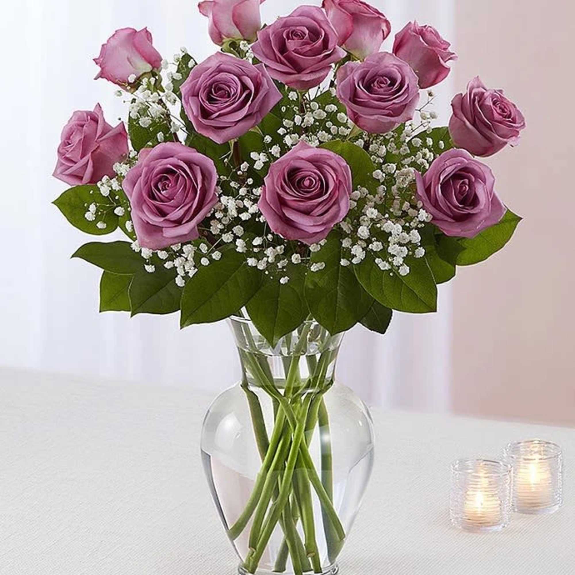 Lavender roses arranged in a clear glass vase with baby's breath