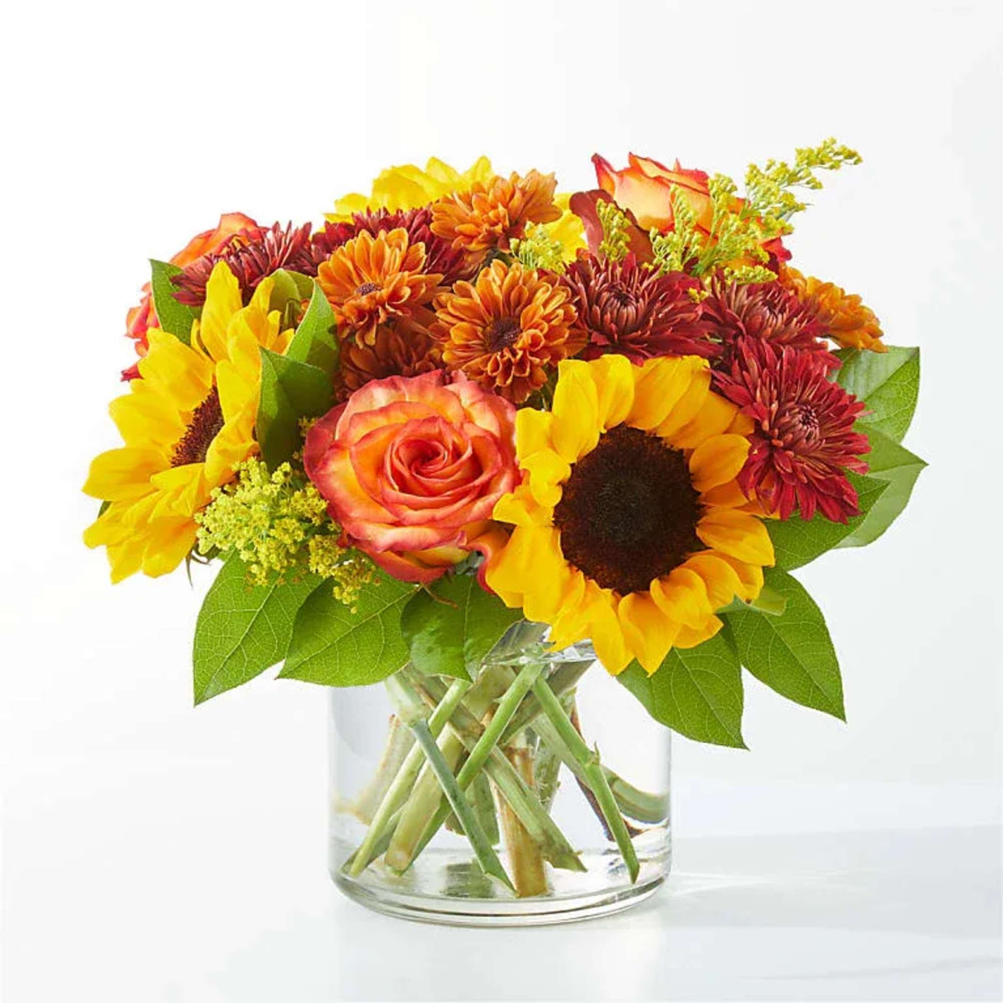 Sunflowers and orange roses in a clear glass vase