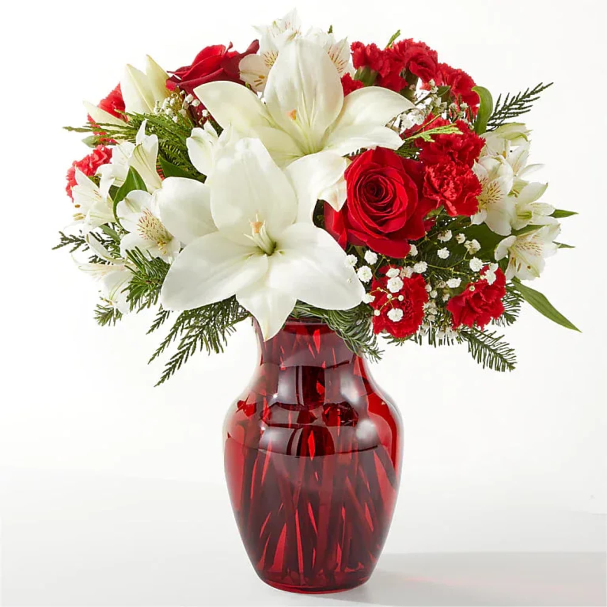 Red and white flower arrangement in a red glass vase