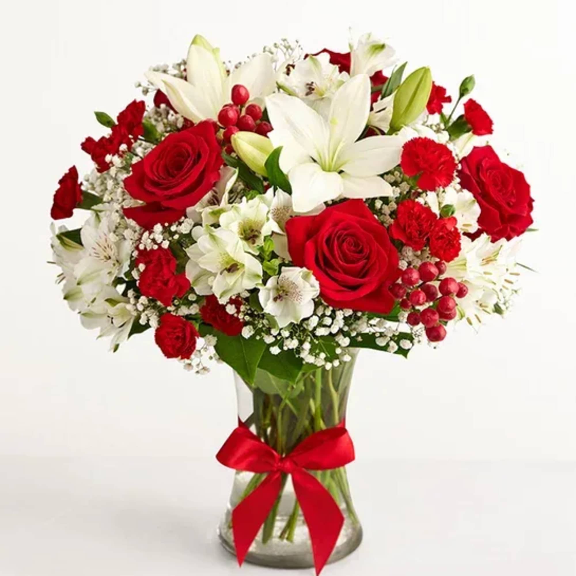 Red roses and white lilies in a glass vase with a red ribbon