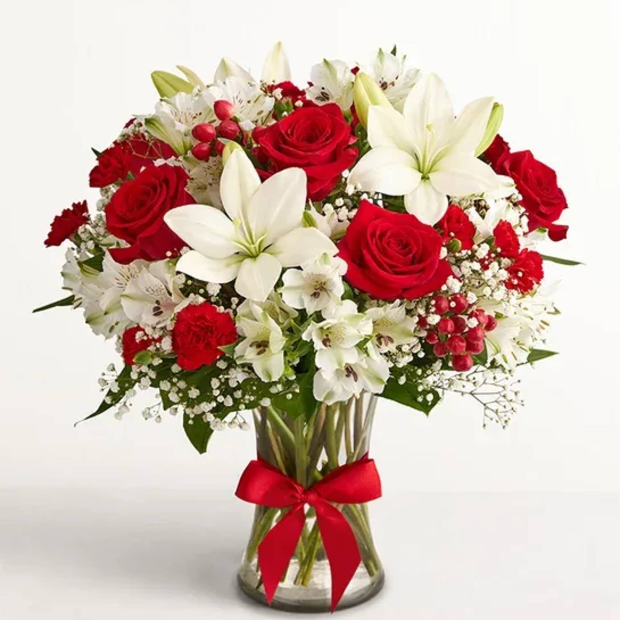 Red roses and white lilies in a glass vase with a red ribbon
