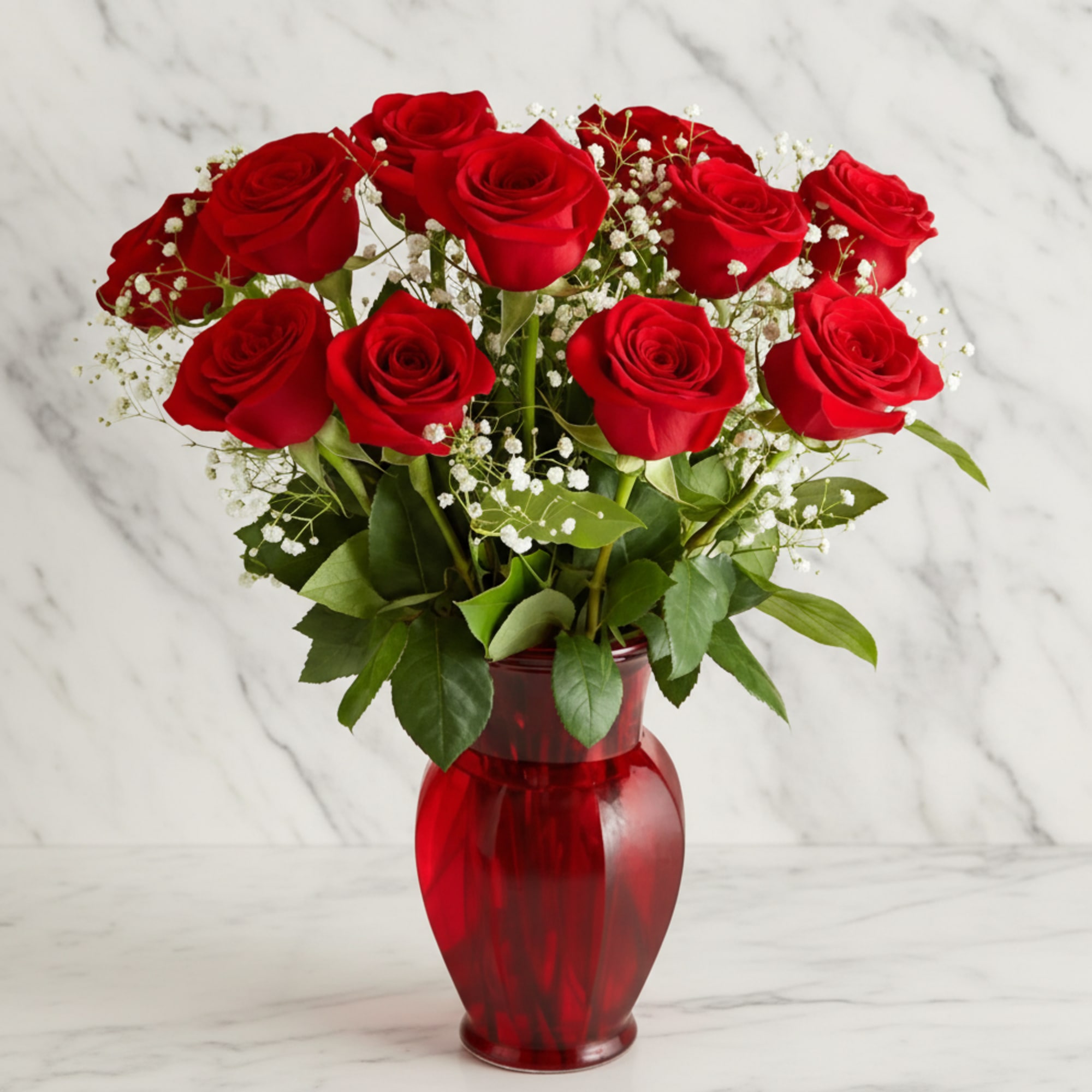 Red roses arranged in a red glass vase with baby's breath