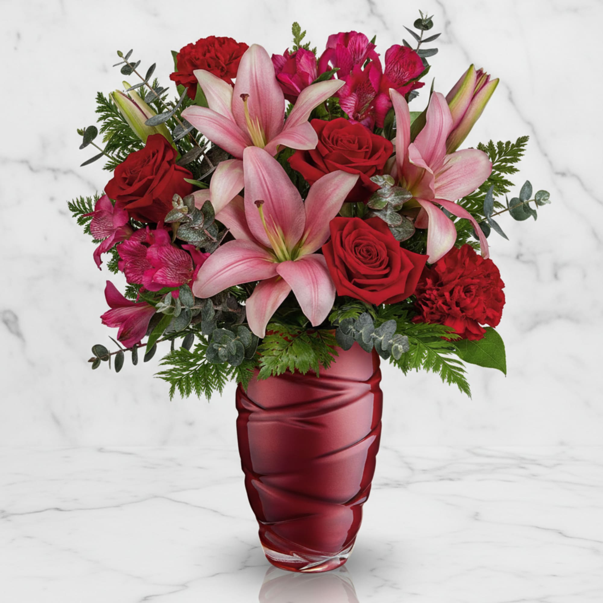 Pink lilies and red roses arranged in a red vase
