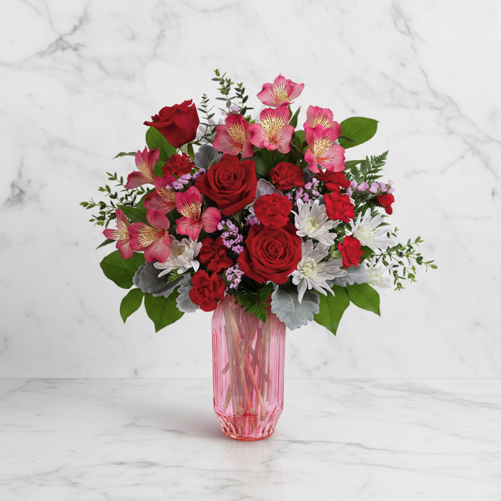 Red and pink mixed bouquet in a pink glass vase