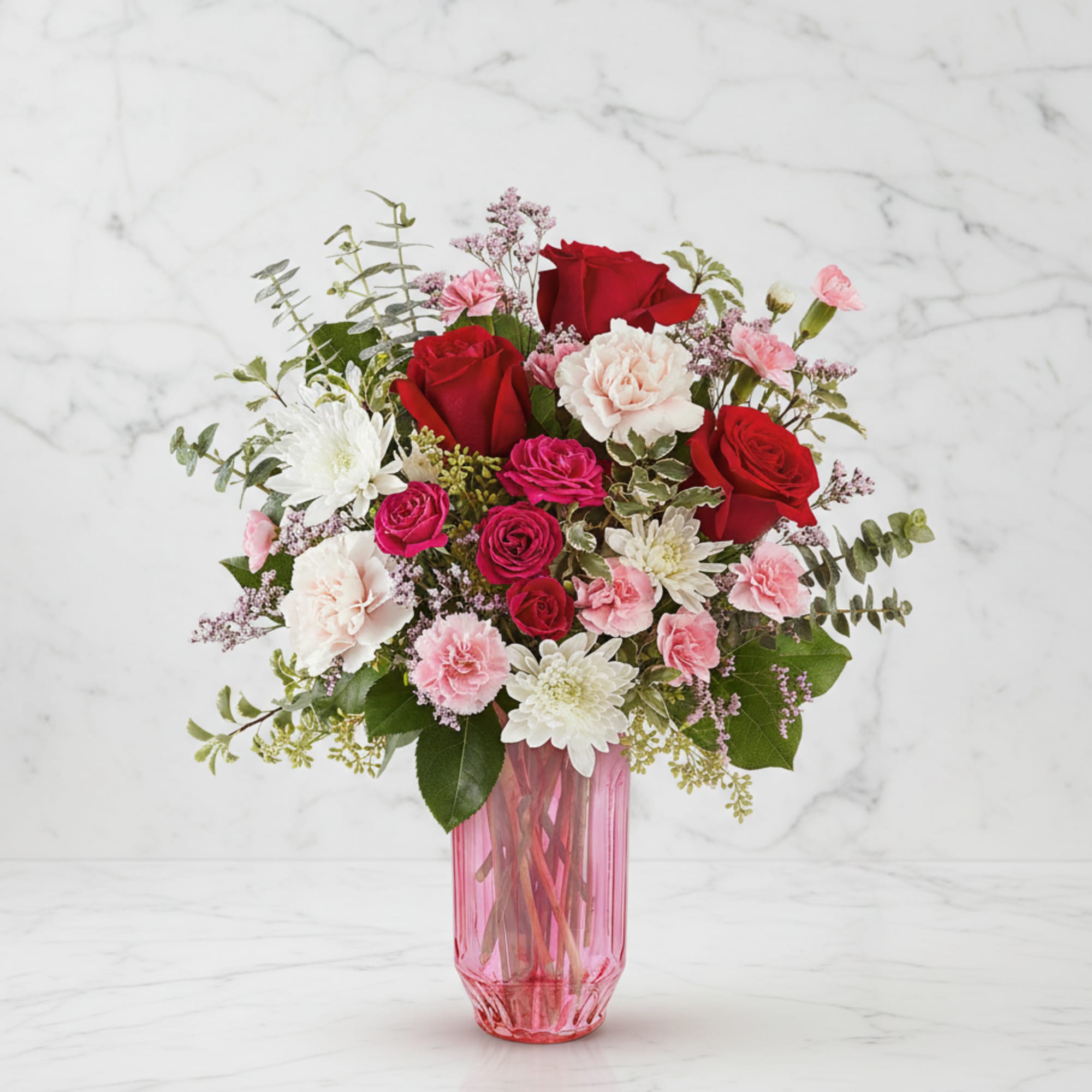 Bouquet of red and pink flowers in a pink glass vase