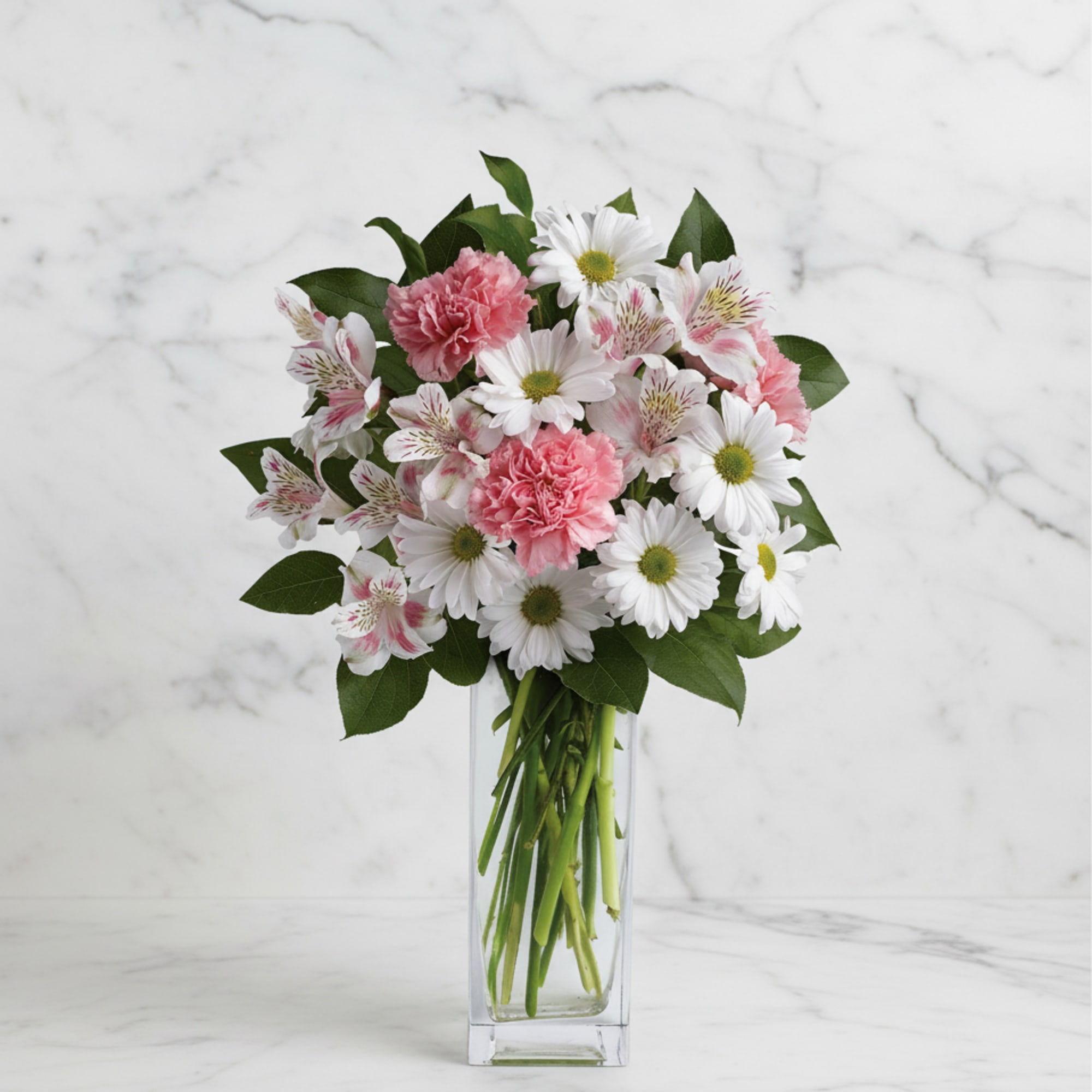 Pink carnations and white daisies in a clear glass vase