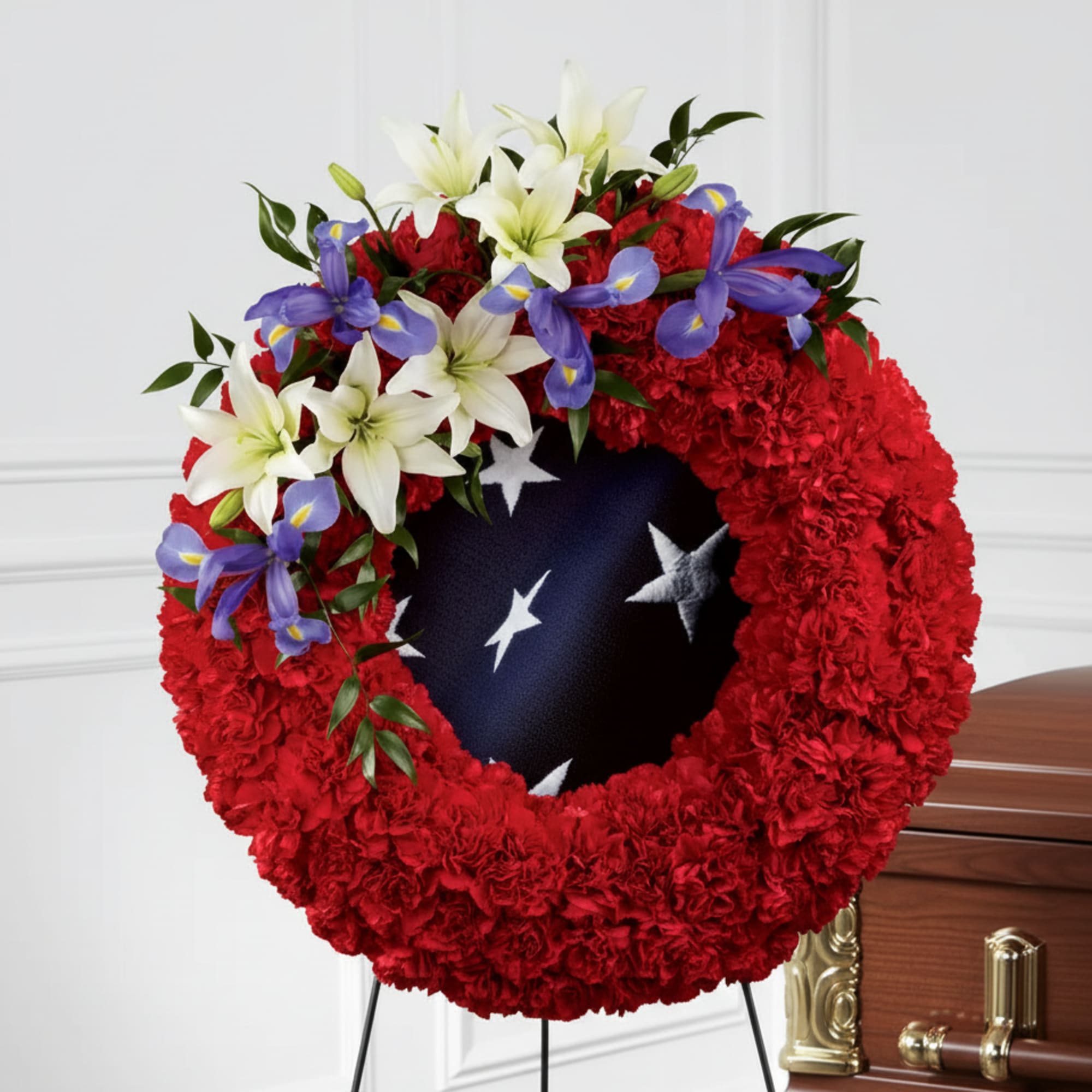 Red floral funeral wreath with white lilies and purple irises on a stand