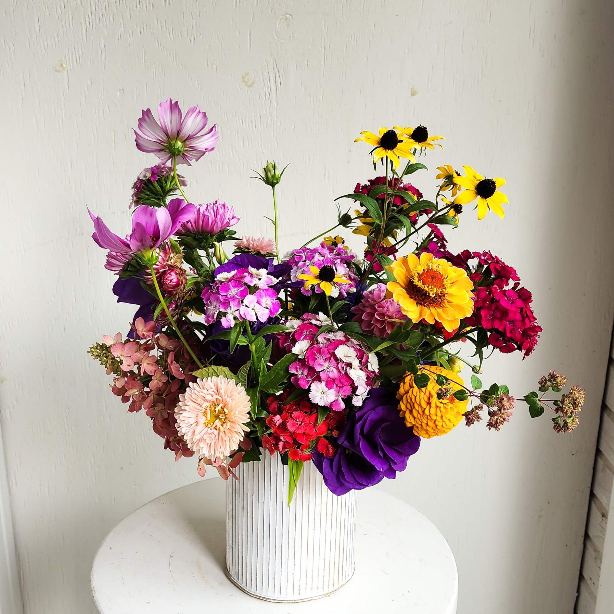 Mixed bouquet in a white ribbed vase with pink, yellow, purple, and red flowers