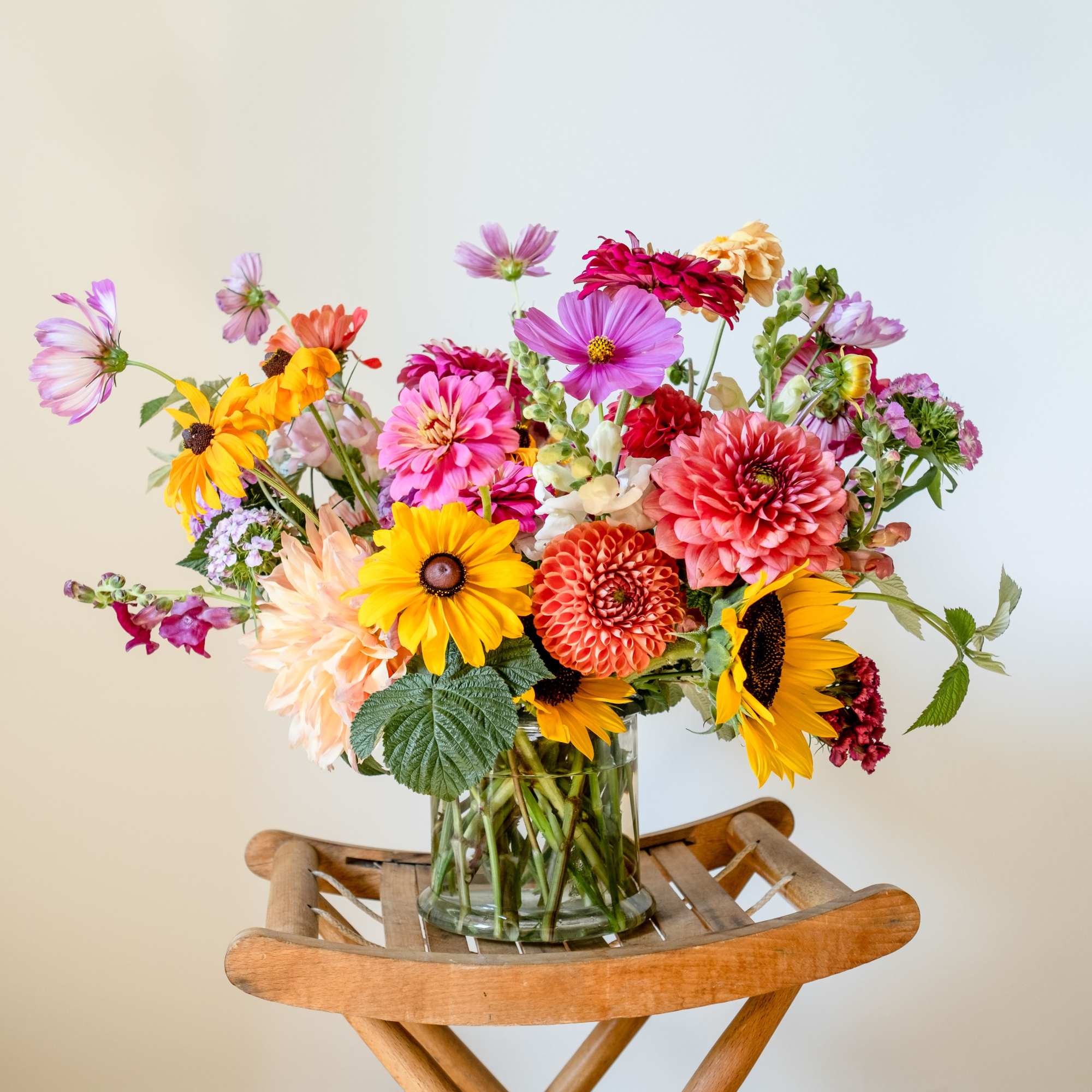 Colorful mixed bouquet in a clear glass vase on a wooden stand