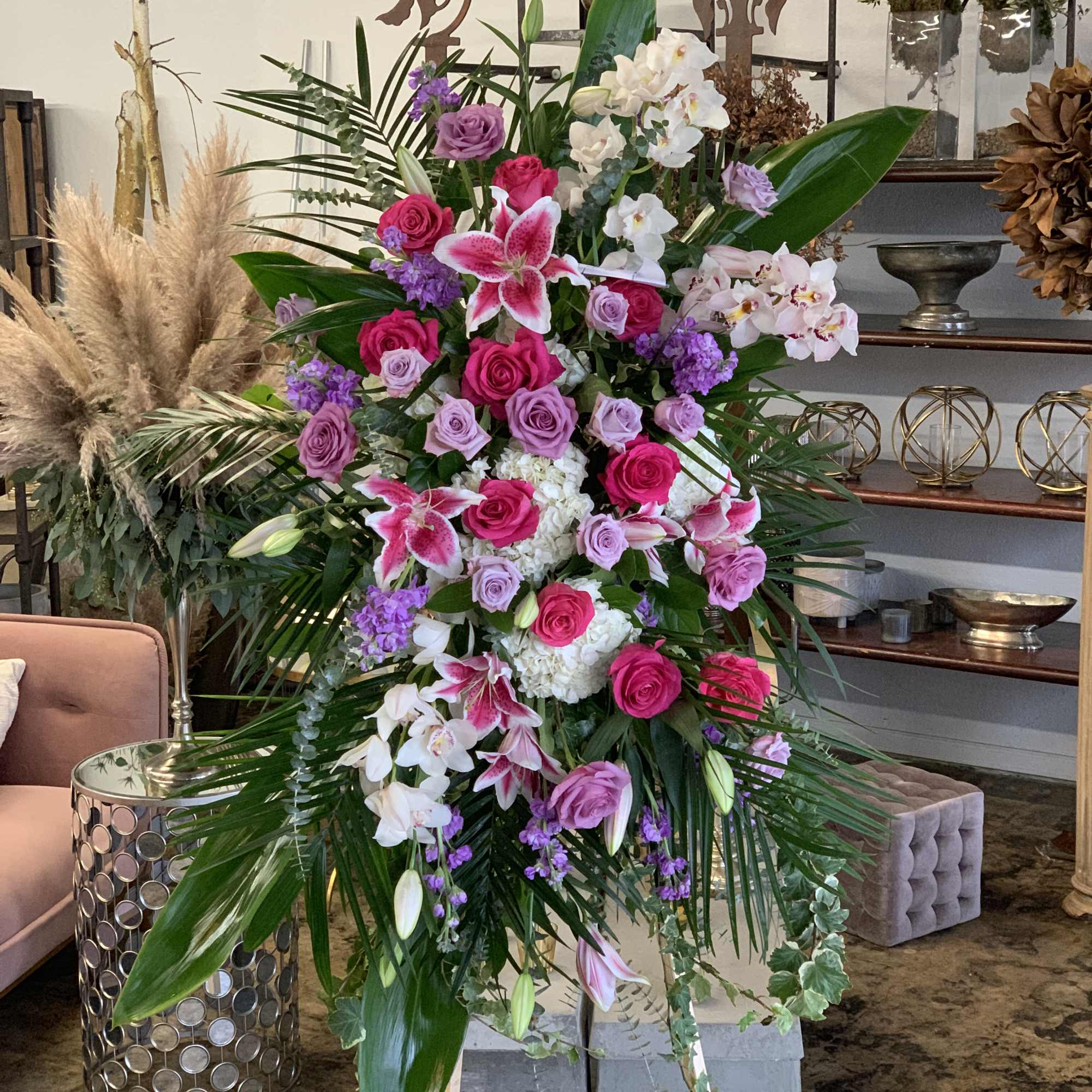 Tall floral standing arrangement with pink roses, orchids, and lilies