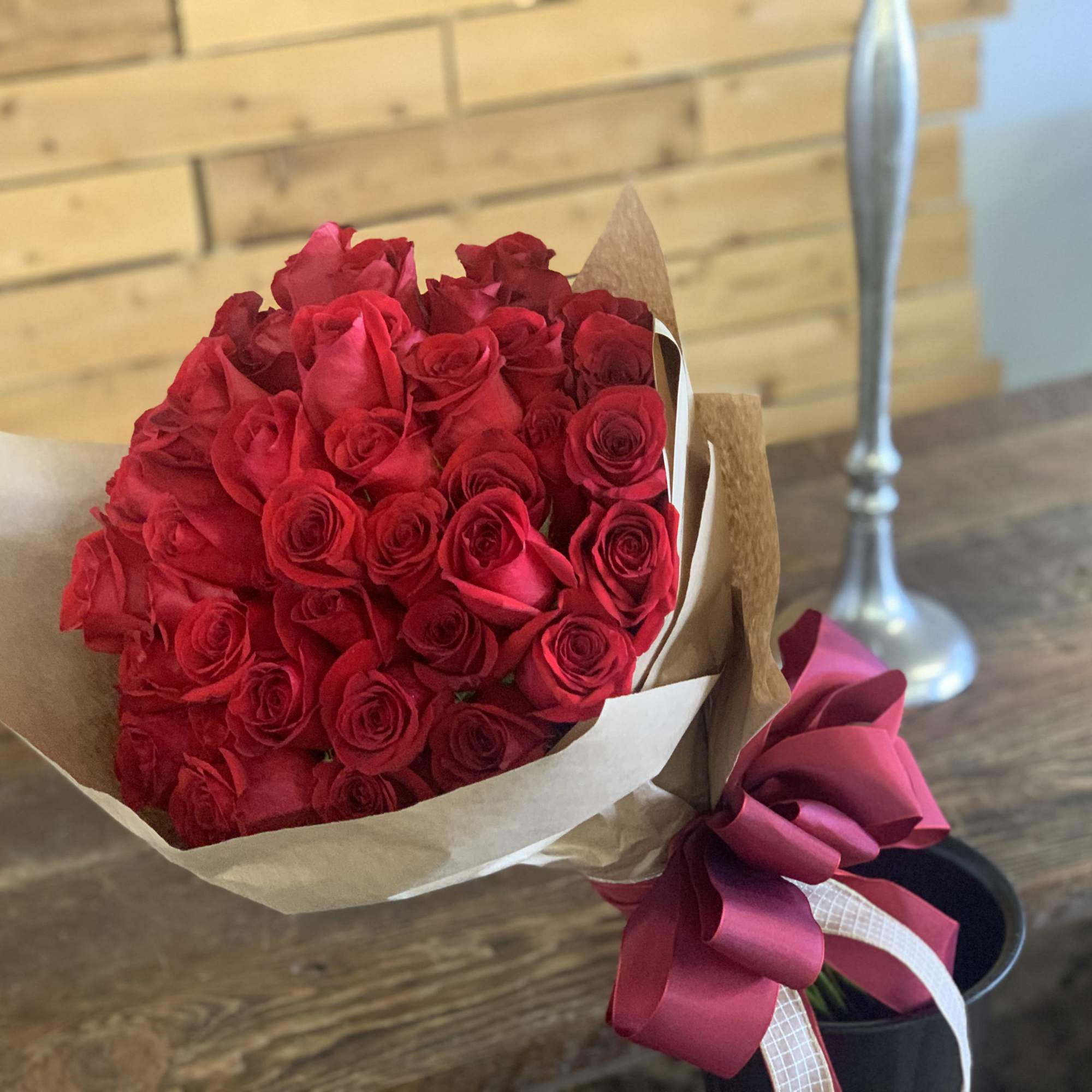 Bouquet of red roses wrapped in brown paper with a pink ribbon