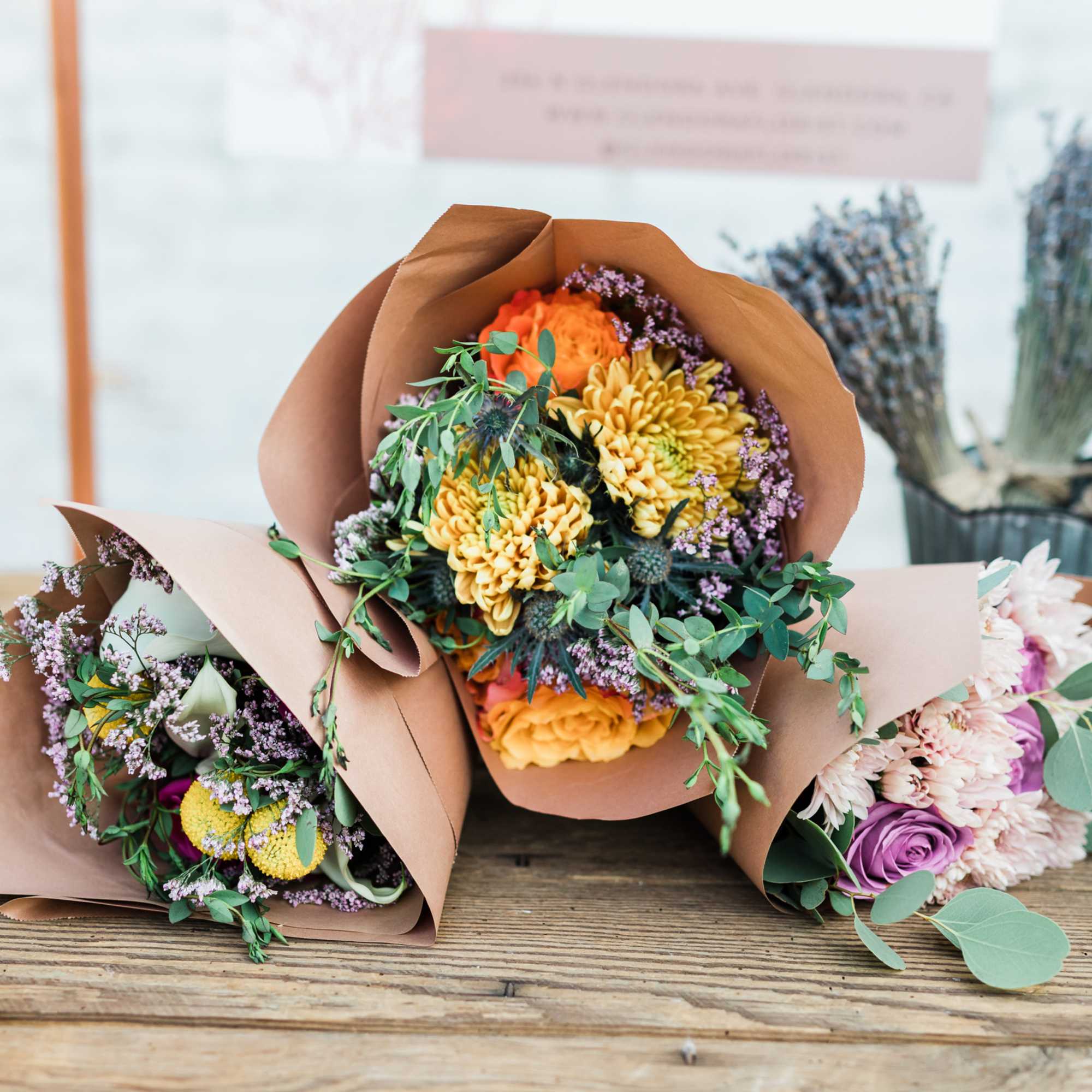 Three wrapped bouquets with orange, yellow, and purple flowers