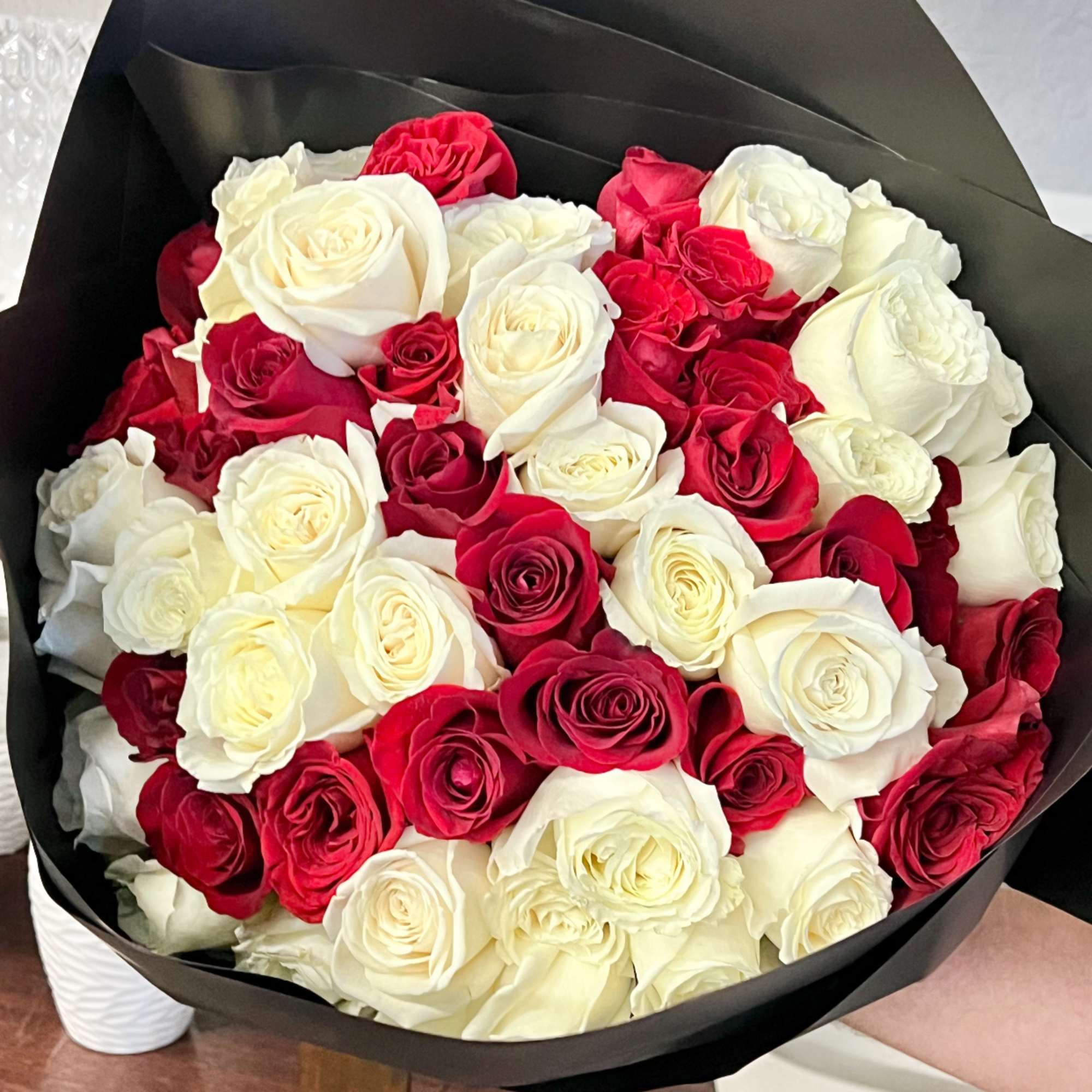 Bouquet of red and white roses wrapped in black paper