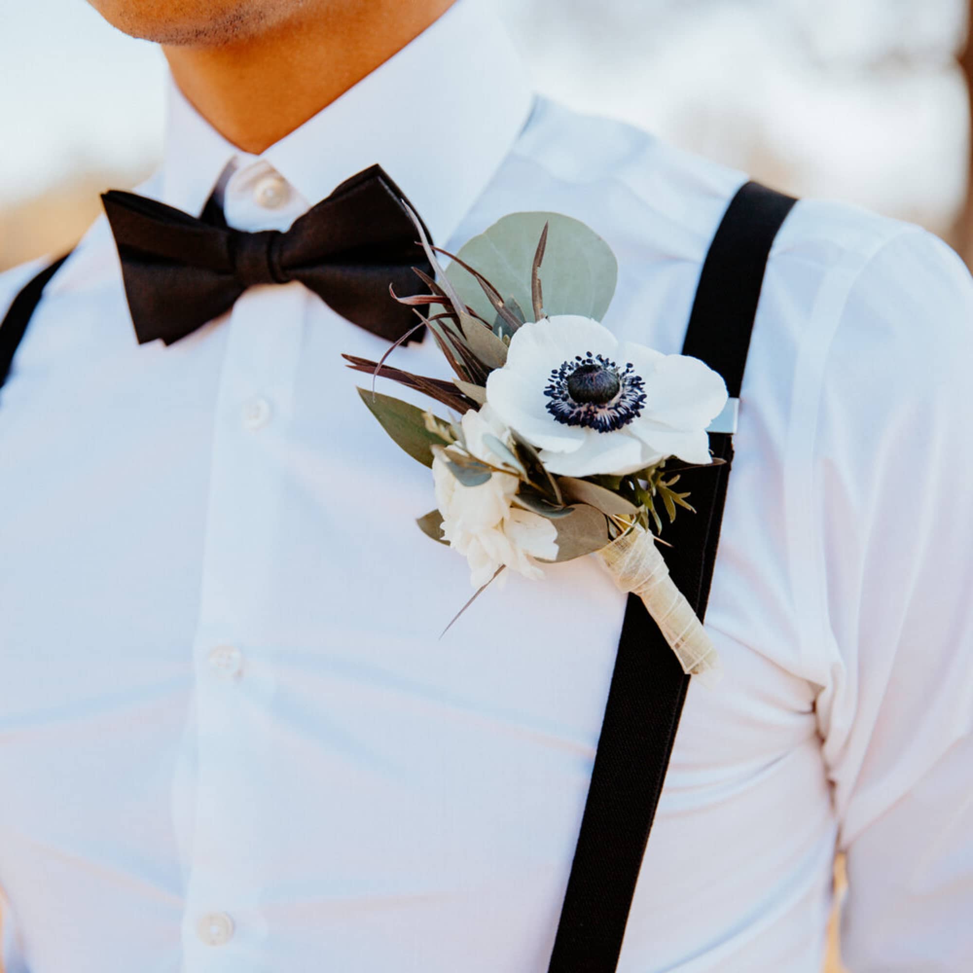 White boutonniere with a dark center pinned to a man's shirt