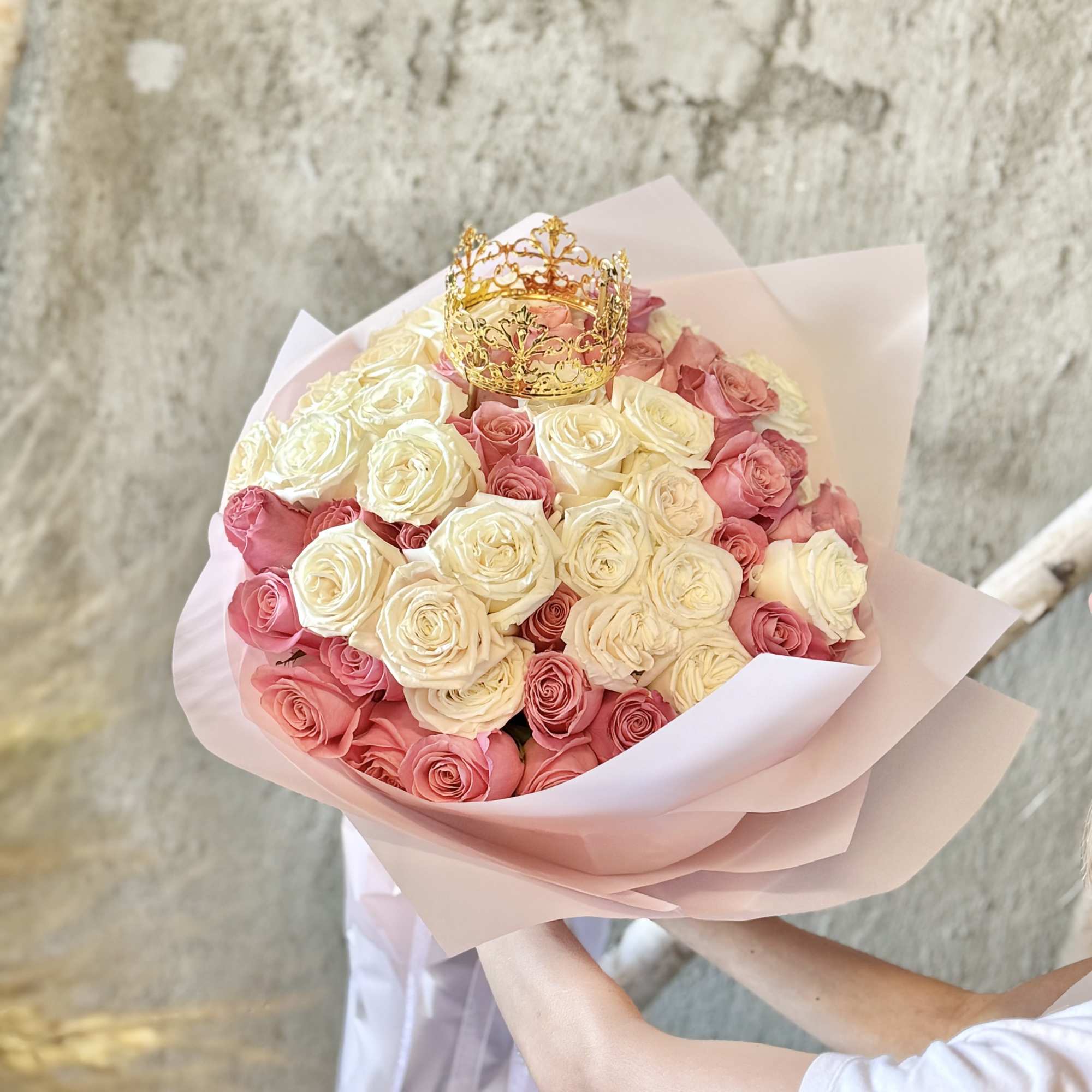 Bouquet of pink and white roses with a gold crown topper